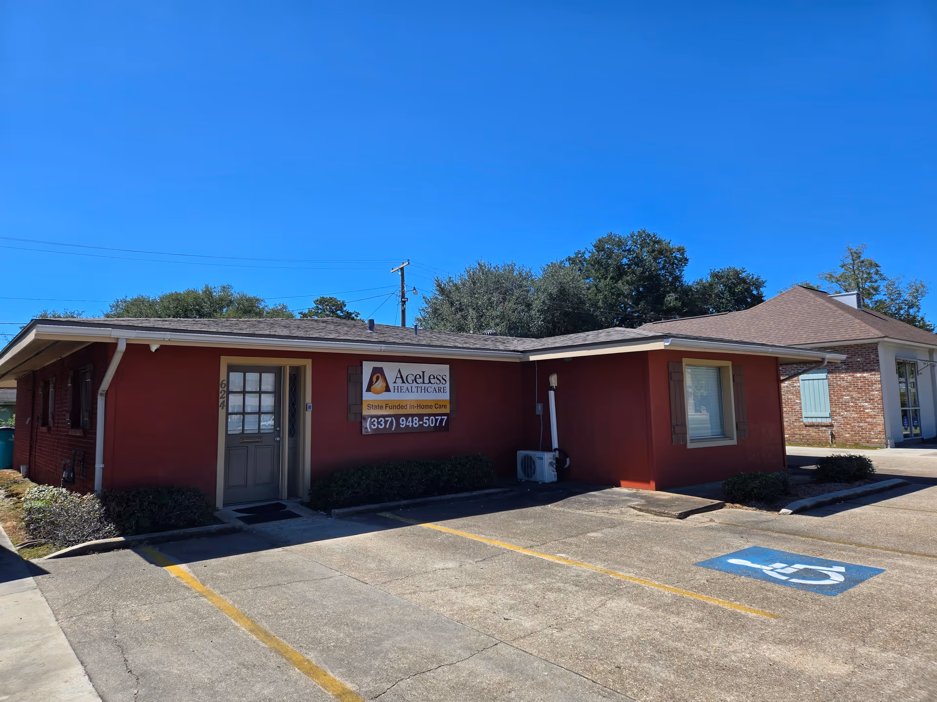 Red, single-story building with Ageless Healthcare sign and adjacent parking area.