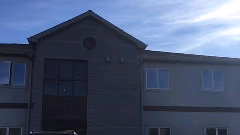 CareGivers America facility exterior: two-story building with gray siding and multiple windows.