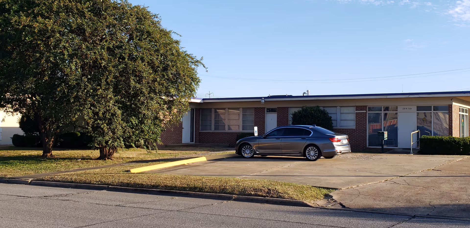 Front view of a single-story brick senior care building with a parked car.