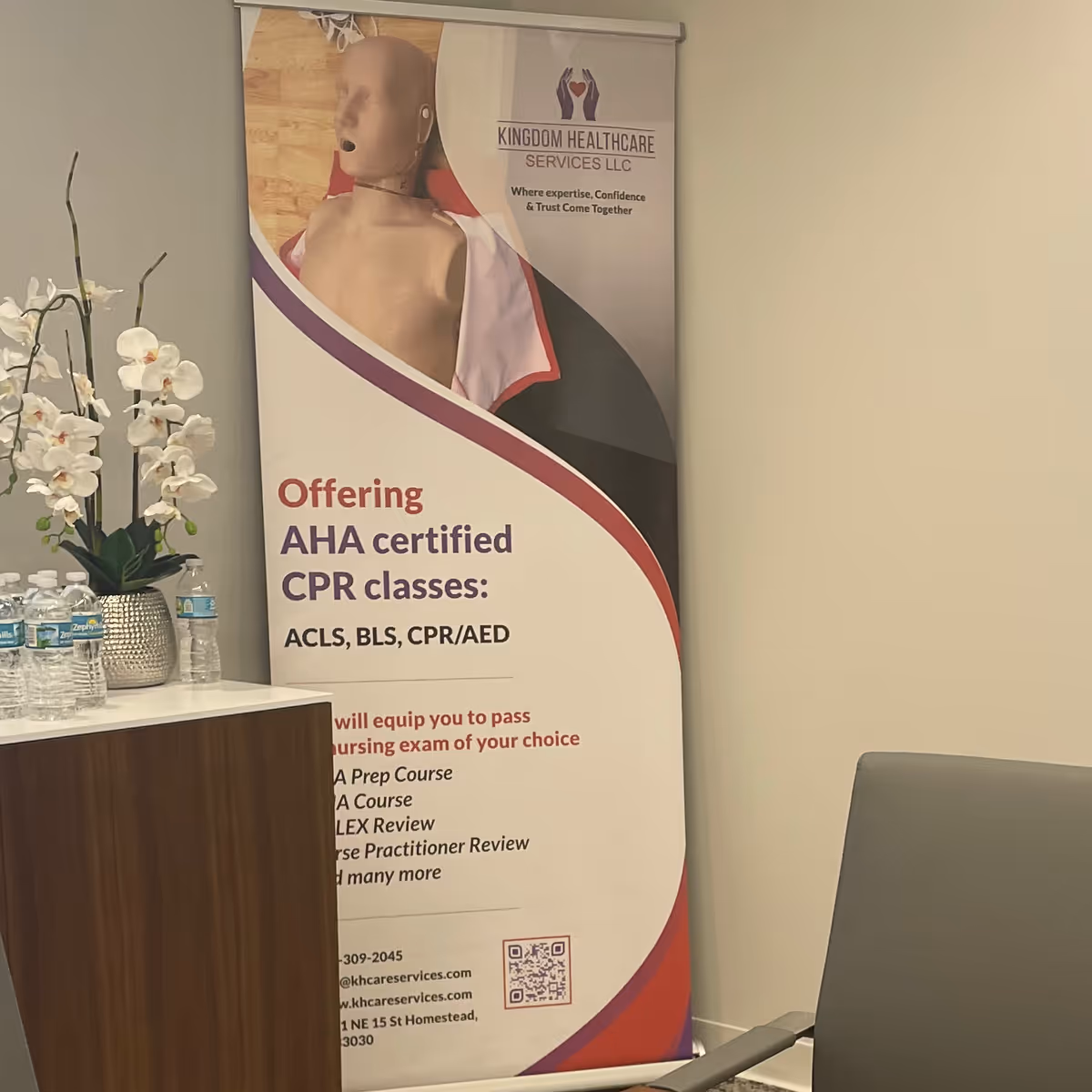 Indoor reception area featuring a CPR classes banner beside a desk and orchids.
