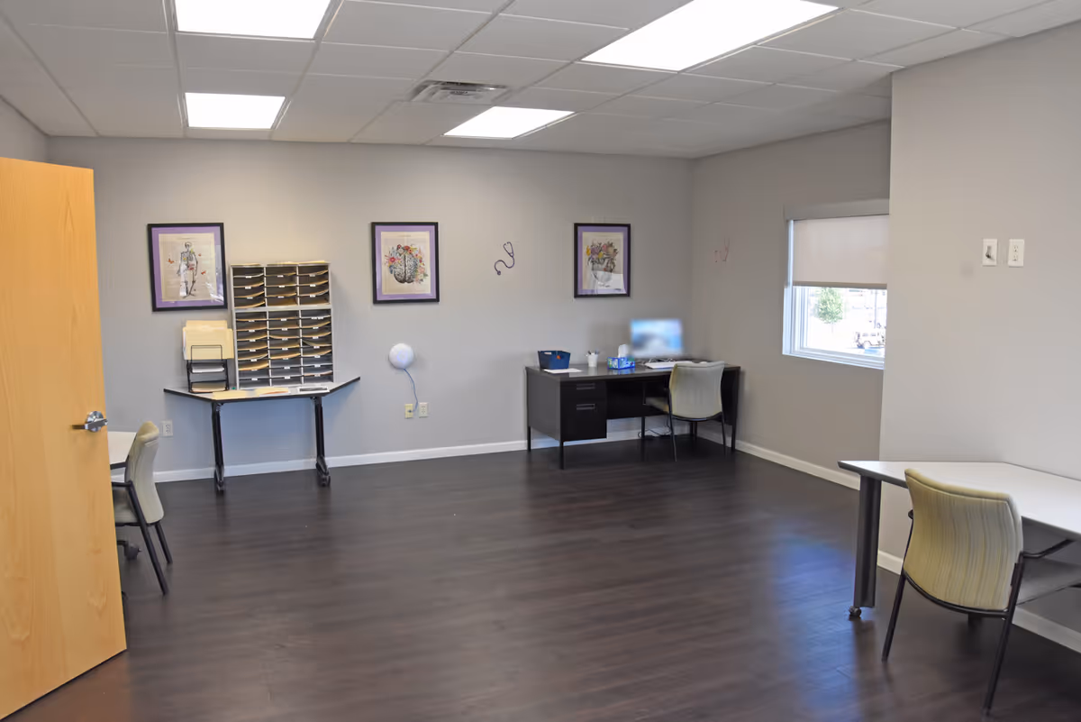 A spacious neutral-color interior room with desks, chairs, and wall art.