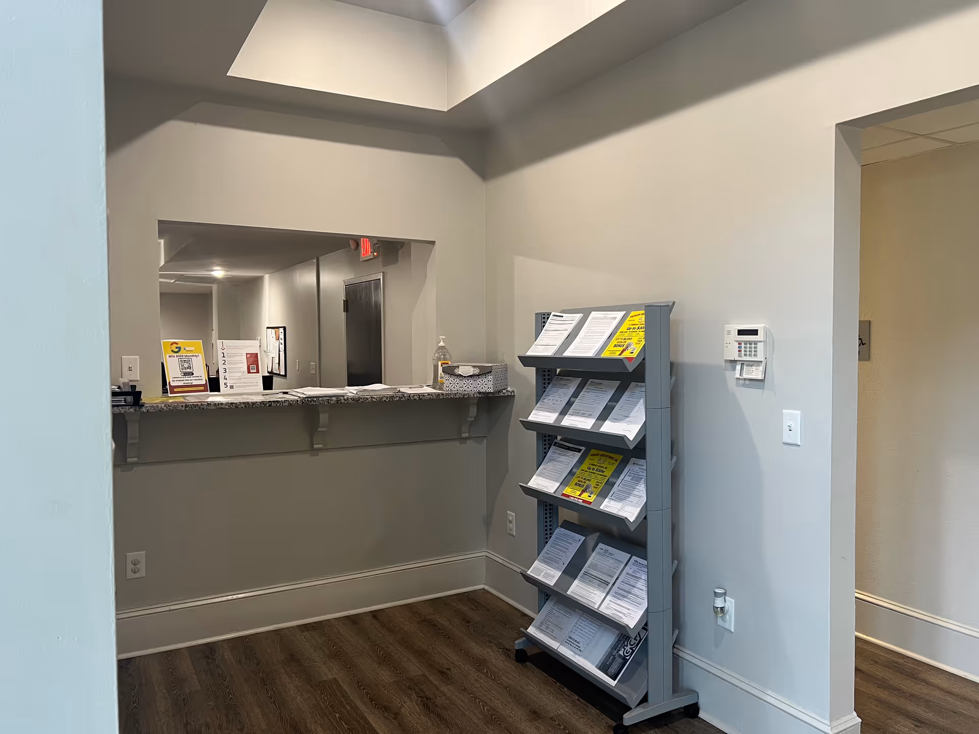 Reception area with a granite counter, brochure rack, and doorway inside a senior facility.