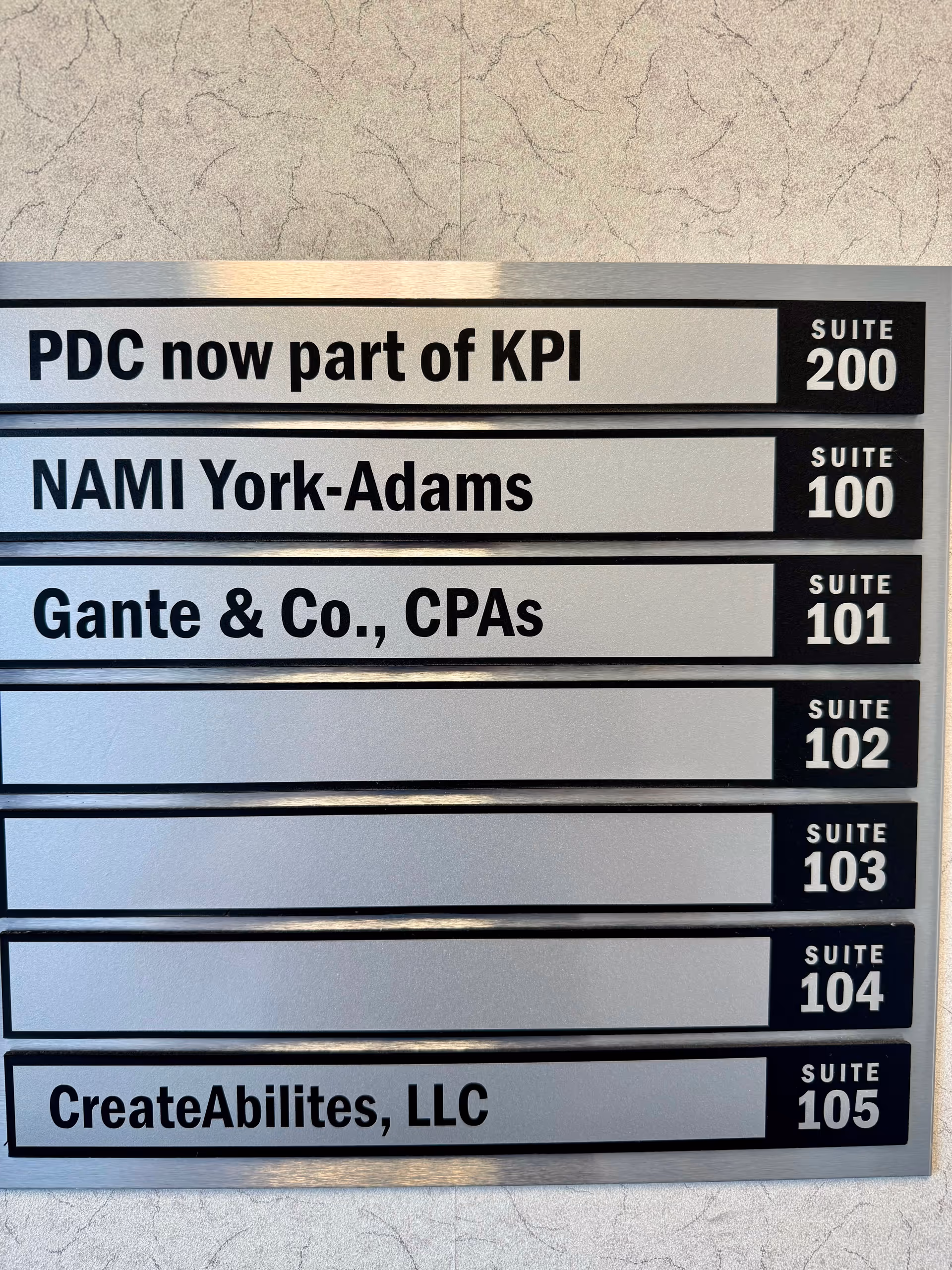 Interior wall directory sign showing several suite numbers and company names.