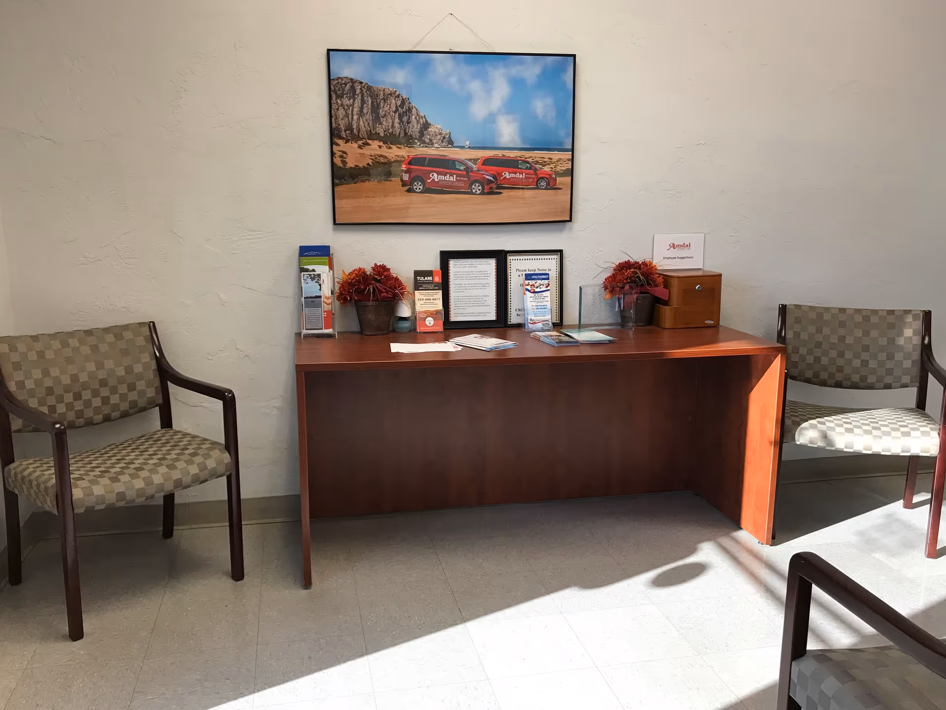 Reception desk with brochures and a framed photo, two checkered chairs in waiting area.