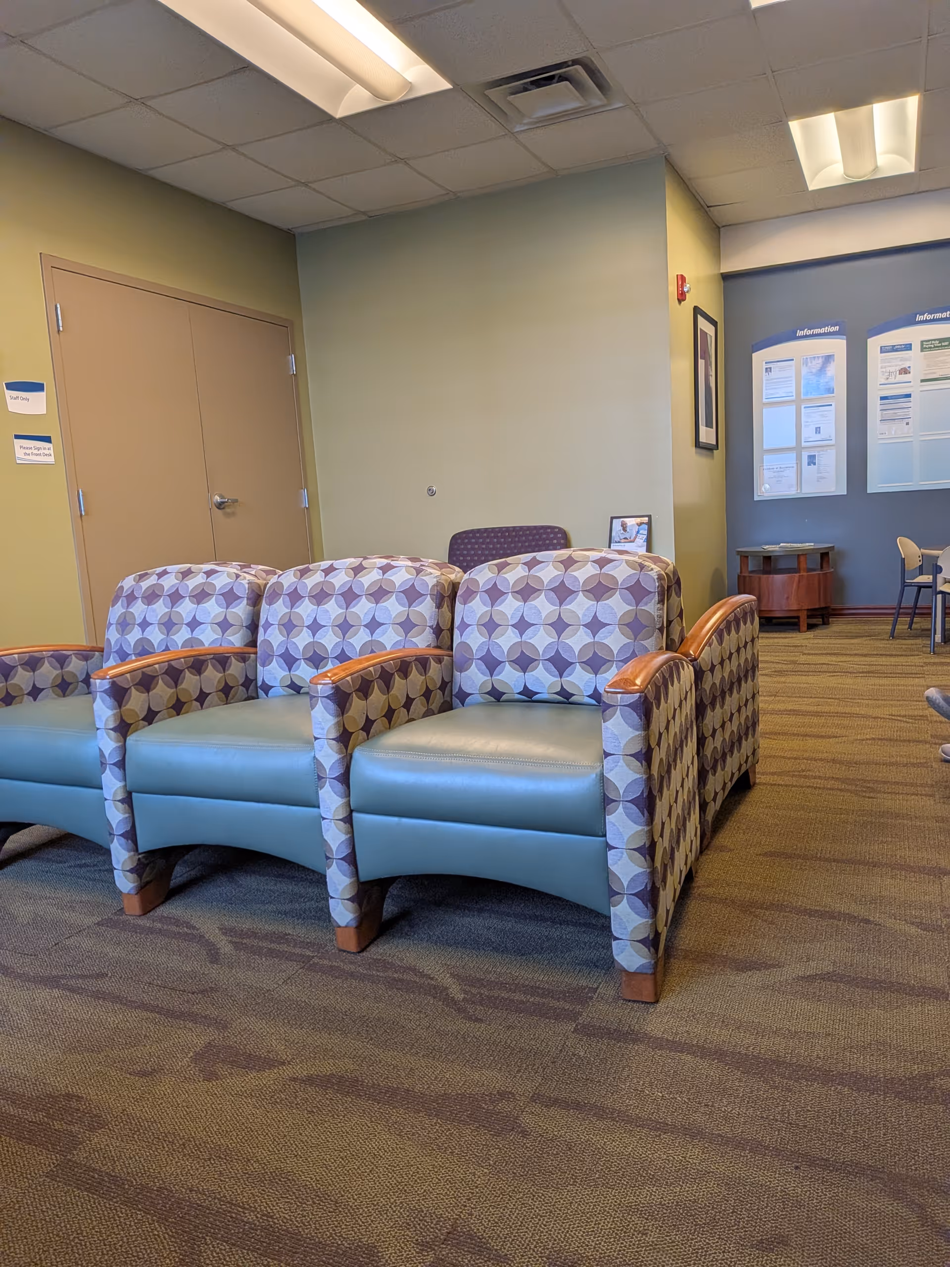 Lobby seating area with patterned chairs and informational boards in a modern facility.