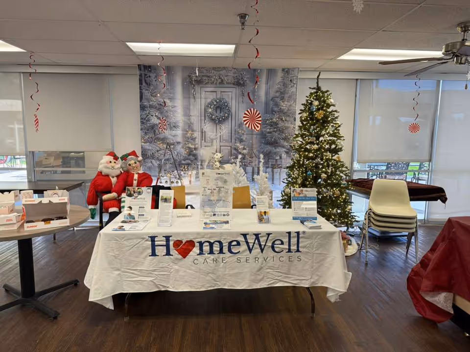 Indoor reception area with a HomeWell Care Services table, Christmas tree, and festive decor.