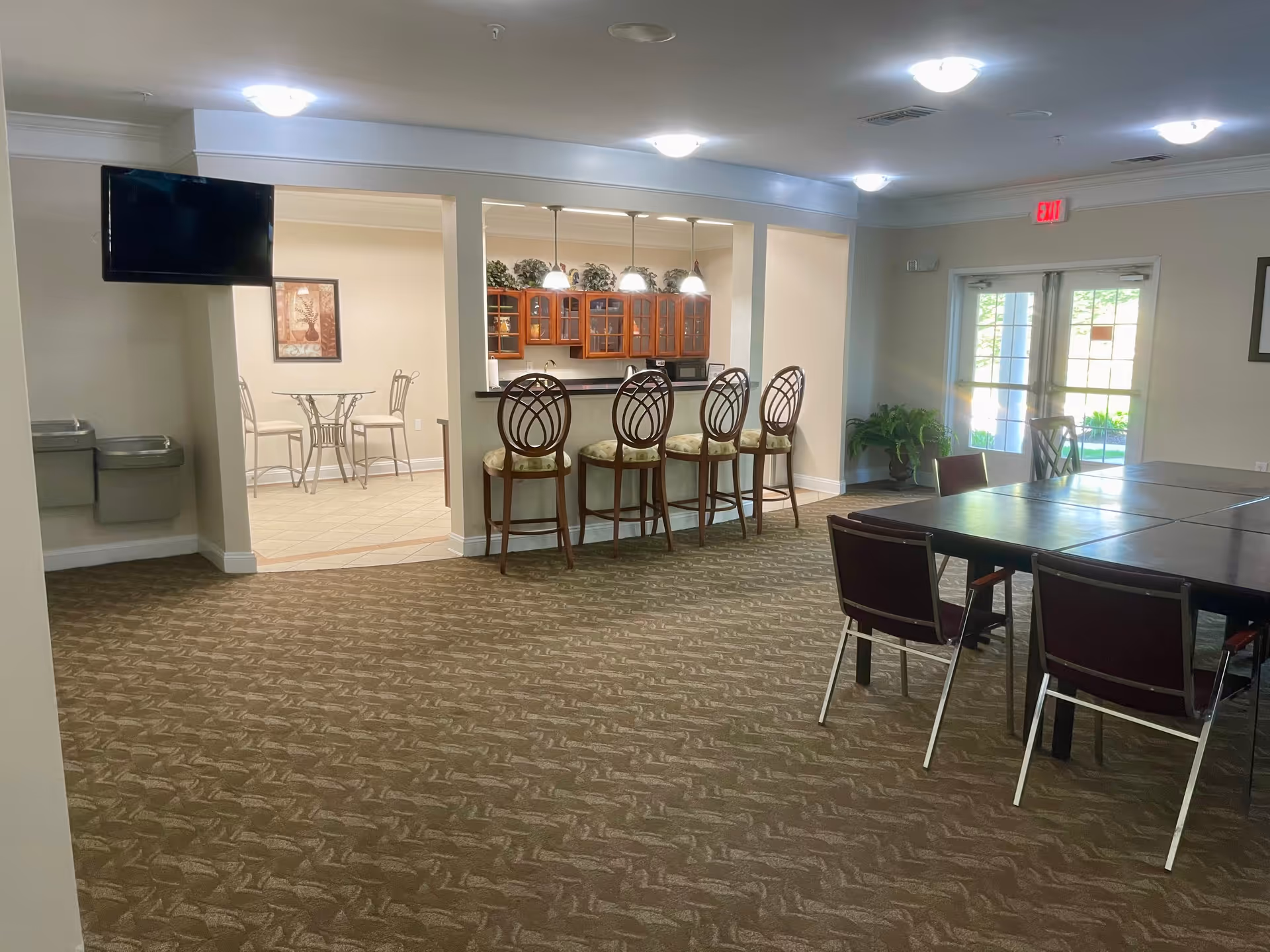 Senior living common area with a bar-height counter, stools, and dining tables.