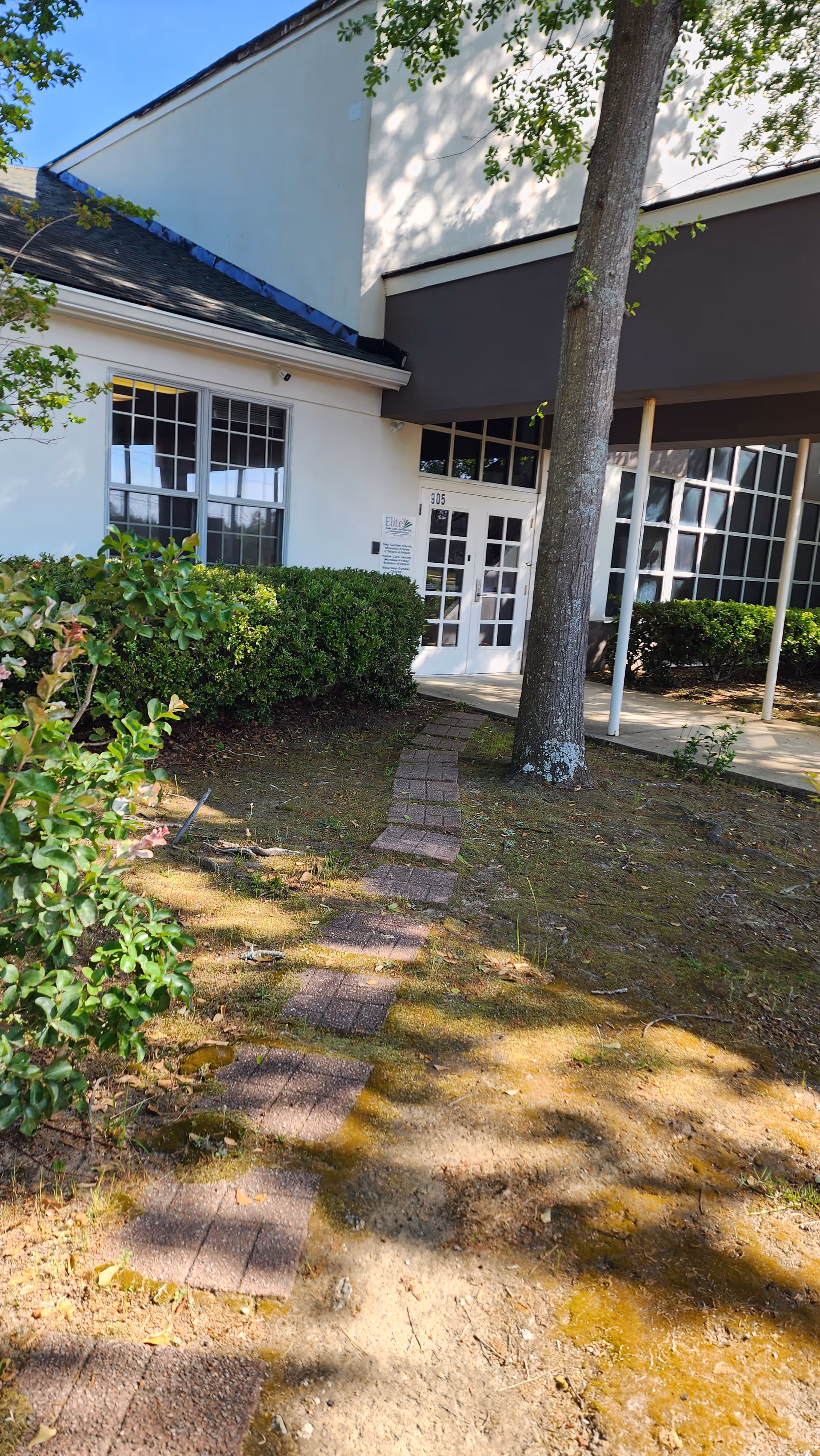 Exterior view of Elite Home Care and Day Centers entrance with a brick path and trees.