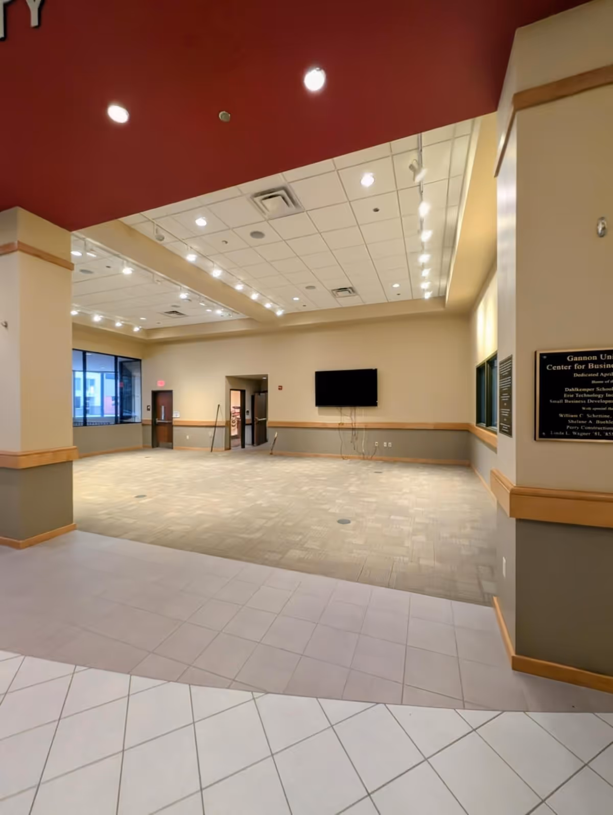 Spacious interior lobby with tiled floor, neutral walls, and a wall-mounted television.