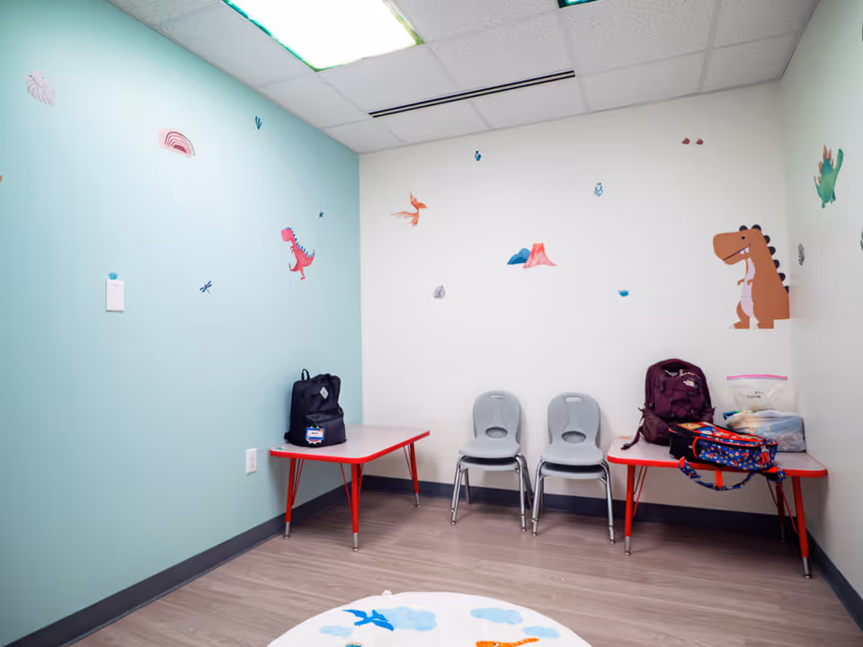 Child-friendly playroom with dinosaur decals and kid-sized tables and chairs.