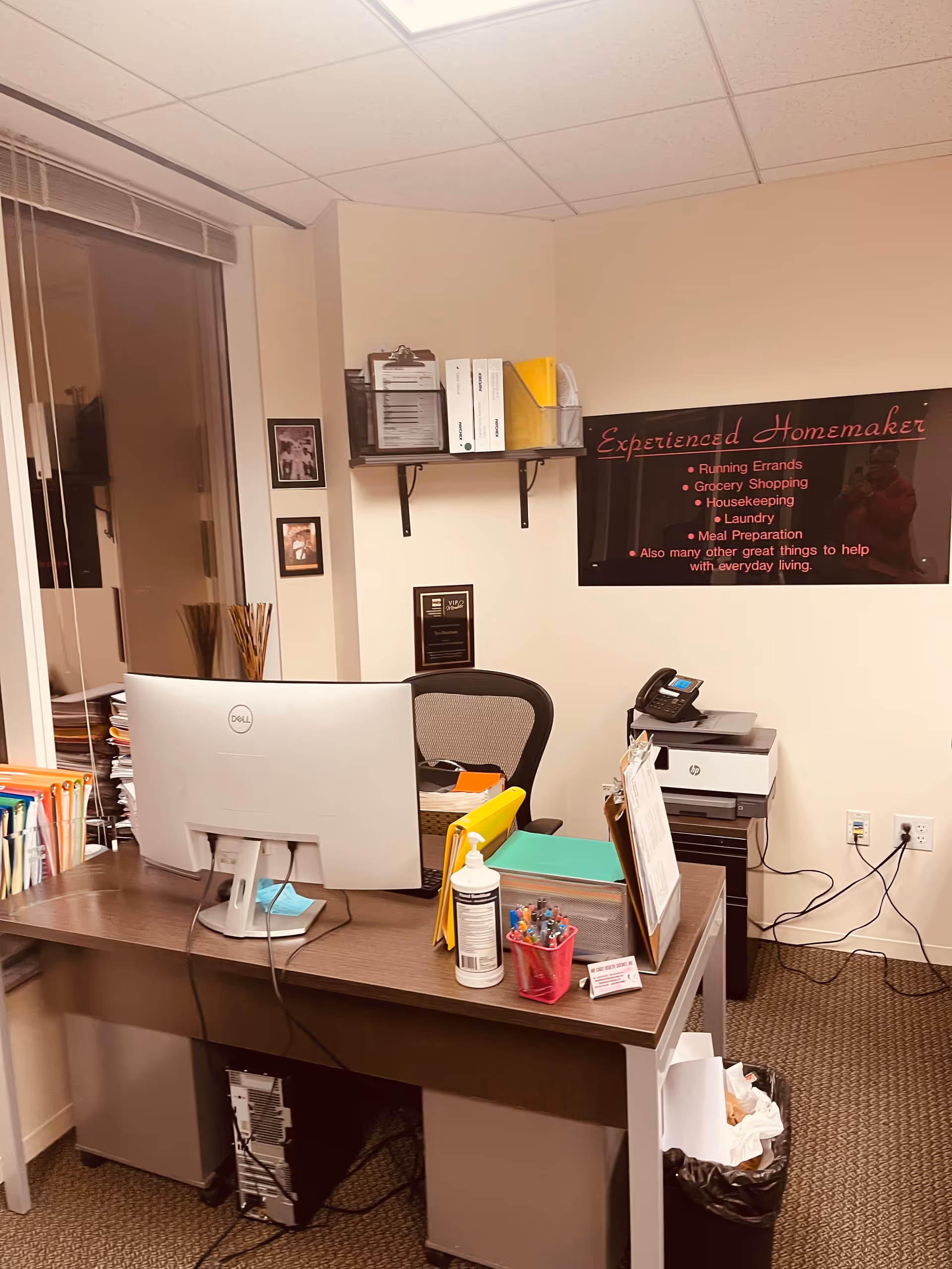 Front desk workspace with computer, printer, and organized supplies in a senior living office.