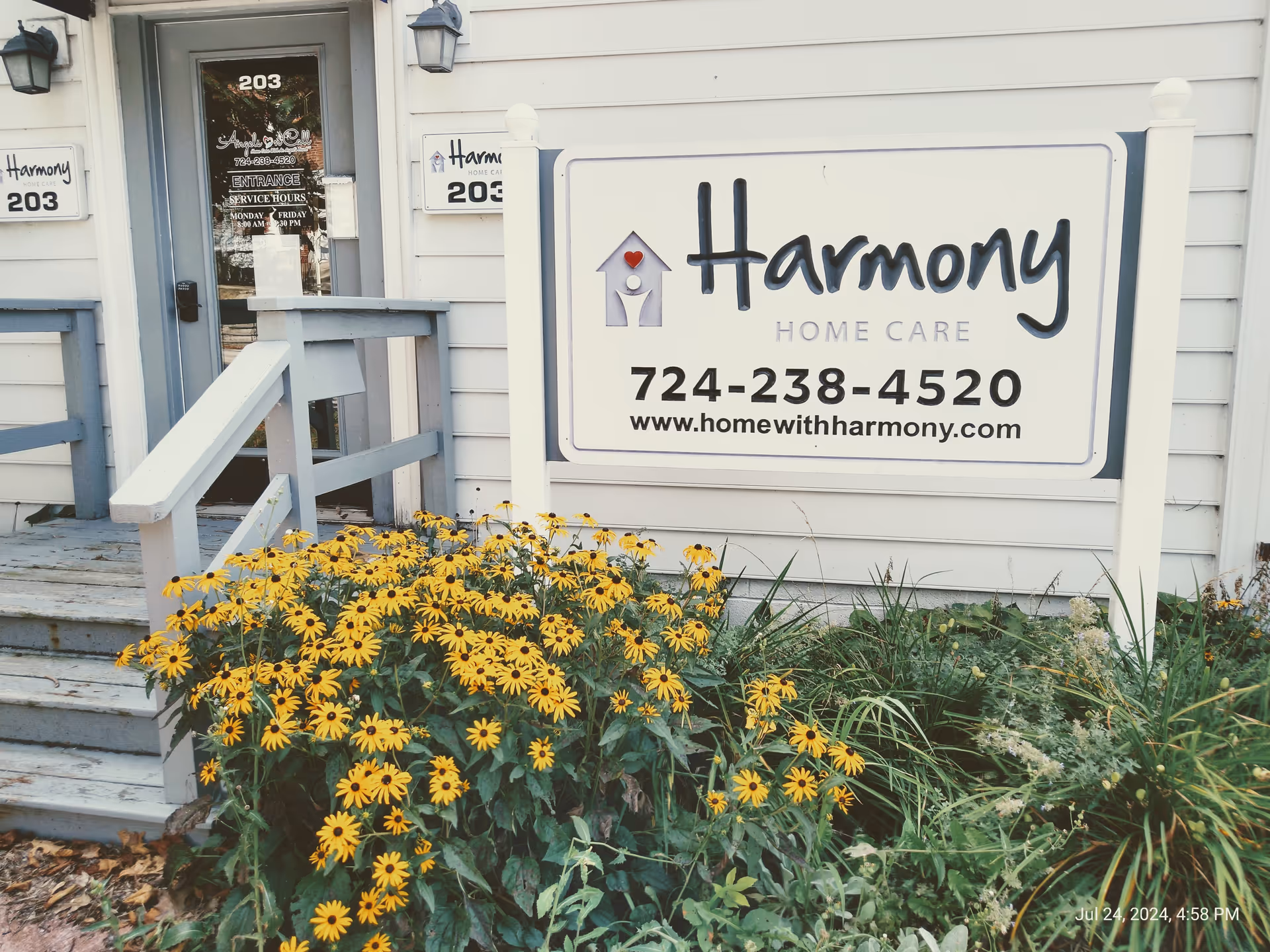 Front view of Harmony Home Care building with sign and yellow flowers in foreground