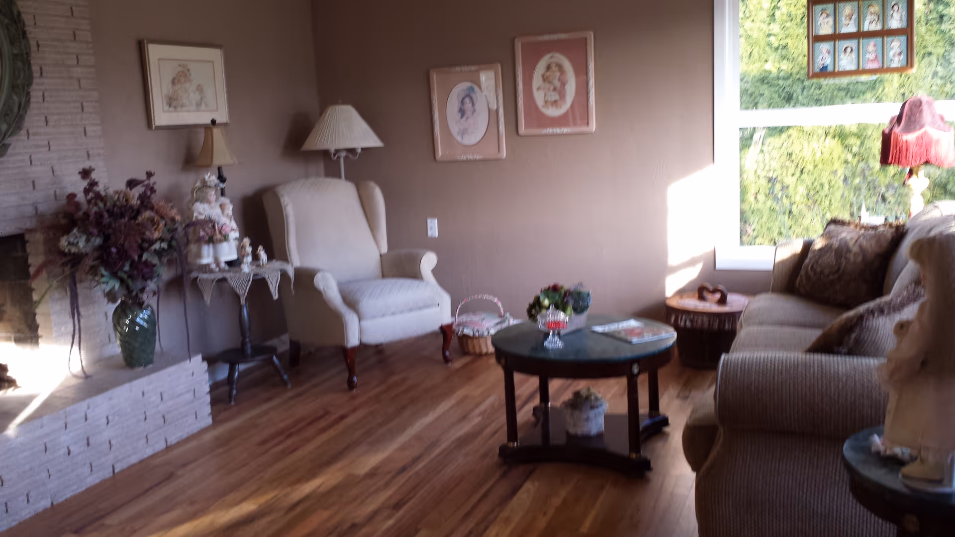 Cozy living room with beige furniture, coffee table, lamps, and a large window.