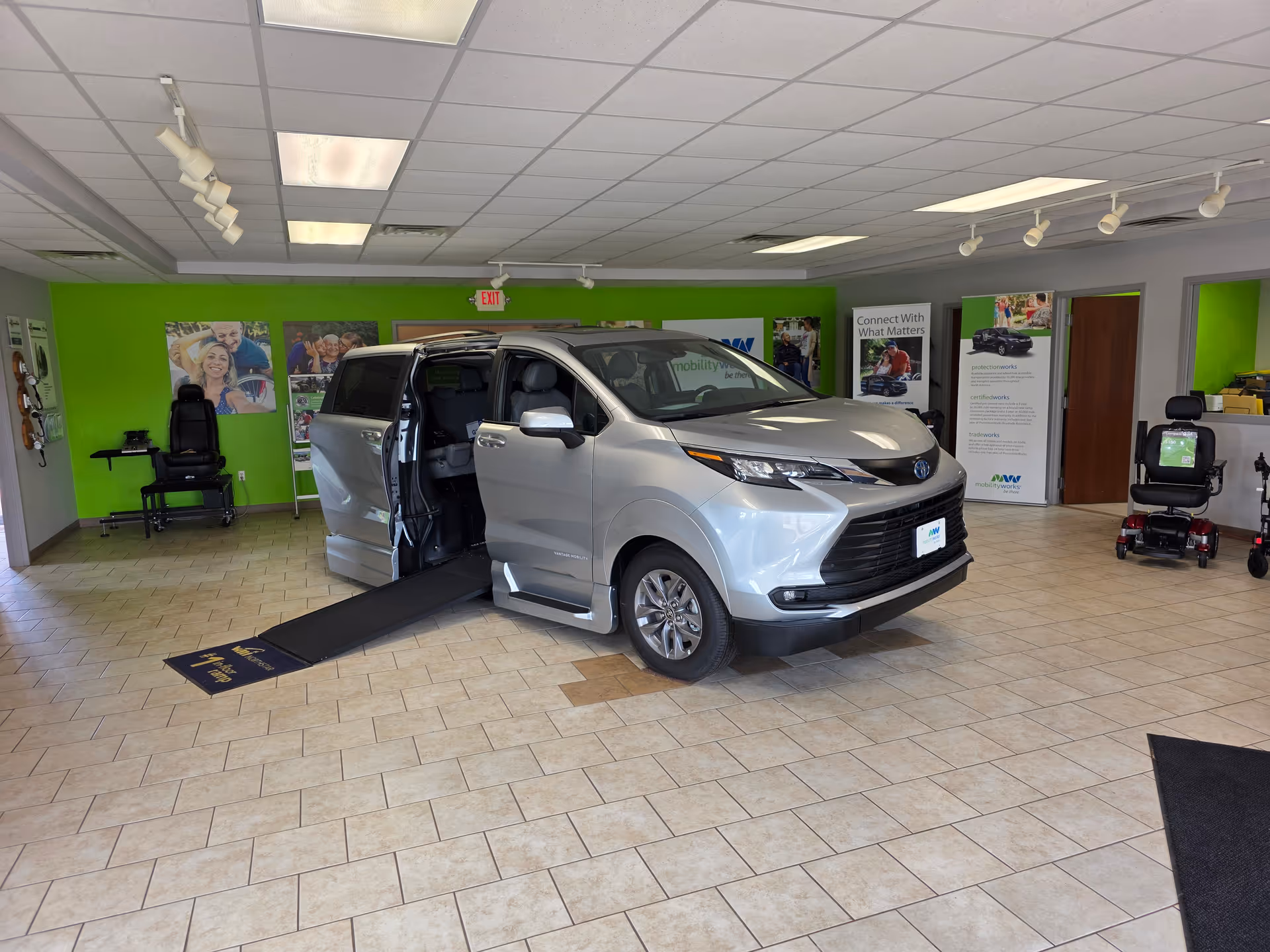 Silver wheelchair-accessible van on a ramp displayed inside MobilityWorks showroom