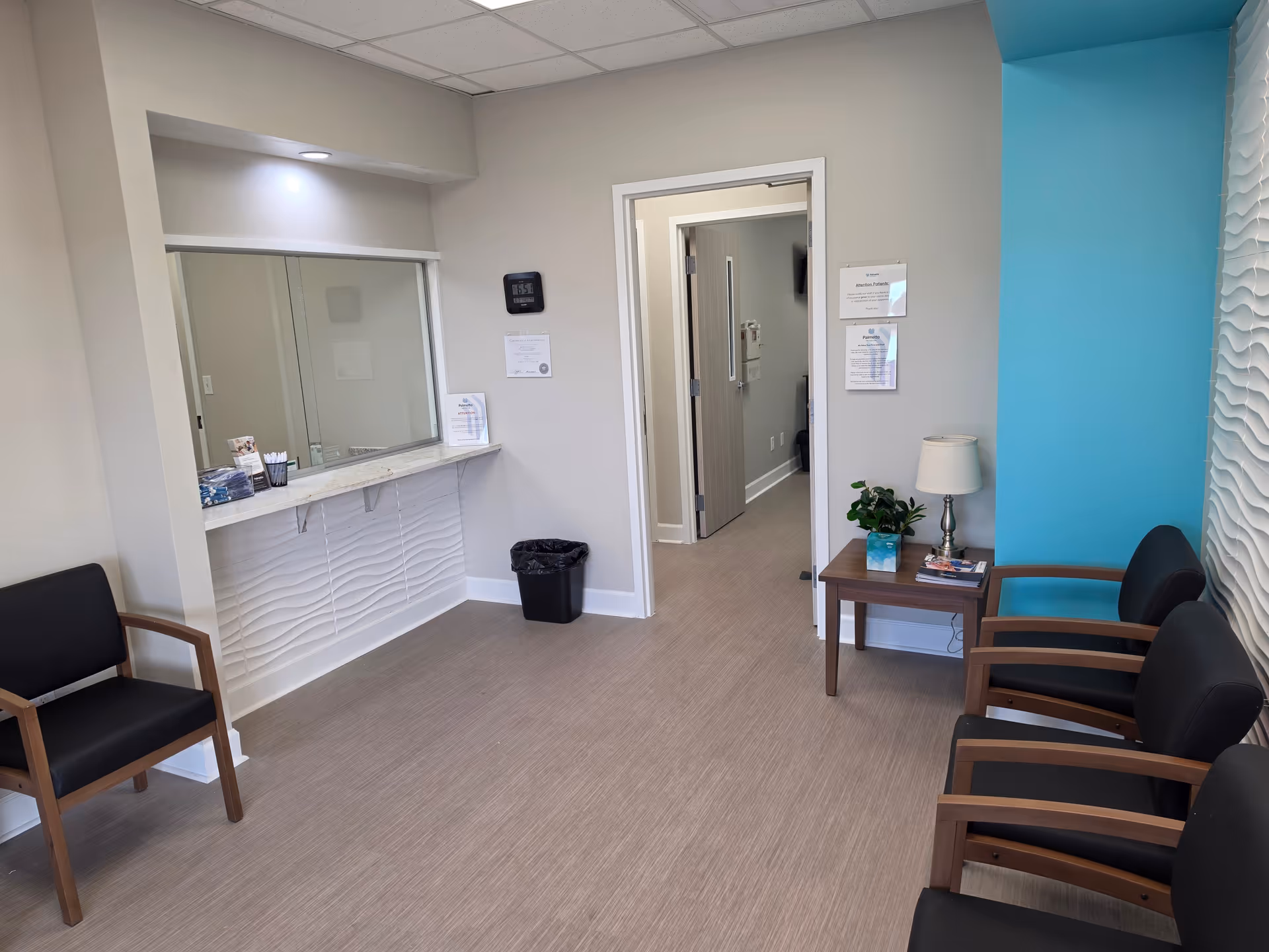 Interior waiting area with a reception counter, chairs, and a turquoise accent wall.
