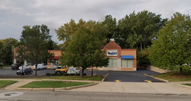 Exterior view of Senior Helpers facility with parking lot and trees.