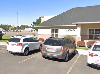CNS Cares facility front facade with several parked cars.