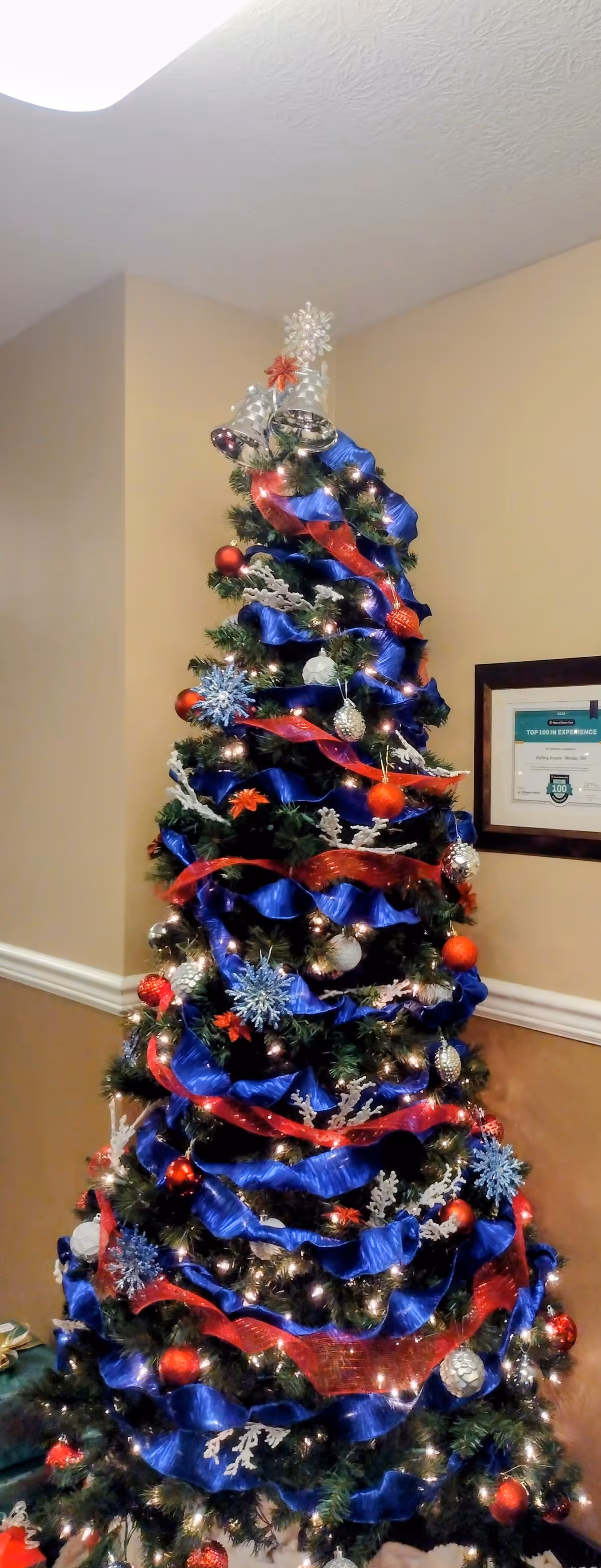 Christmas tree with blue and red ribbons decorates a hallway at Visiting Angels Senior Home Care