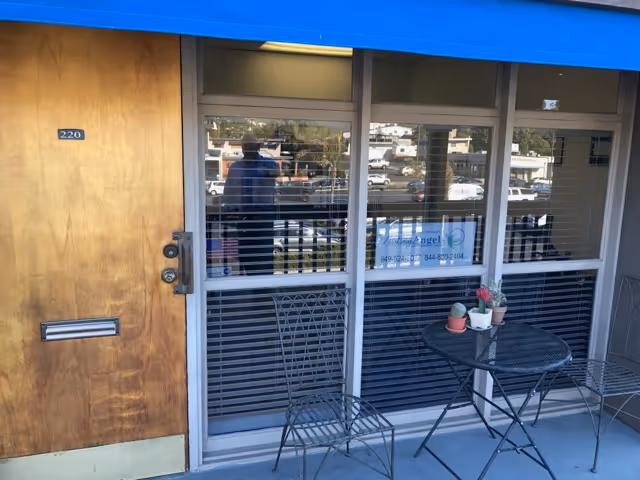 Outdoor seating area with a metal table and chairs in front of the Visiting Angels entrance.