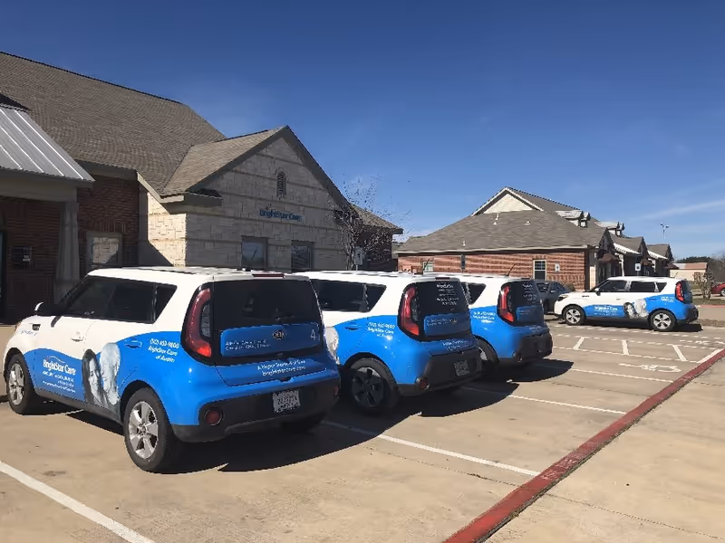 BrightStar Care branded blue-and-white vans parked along the exterior of a single-story facility.