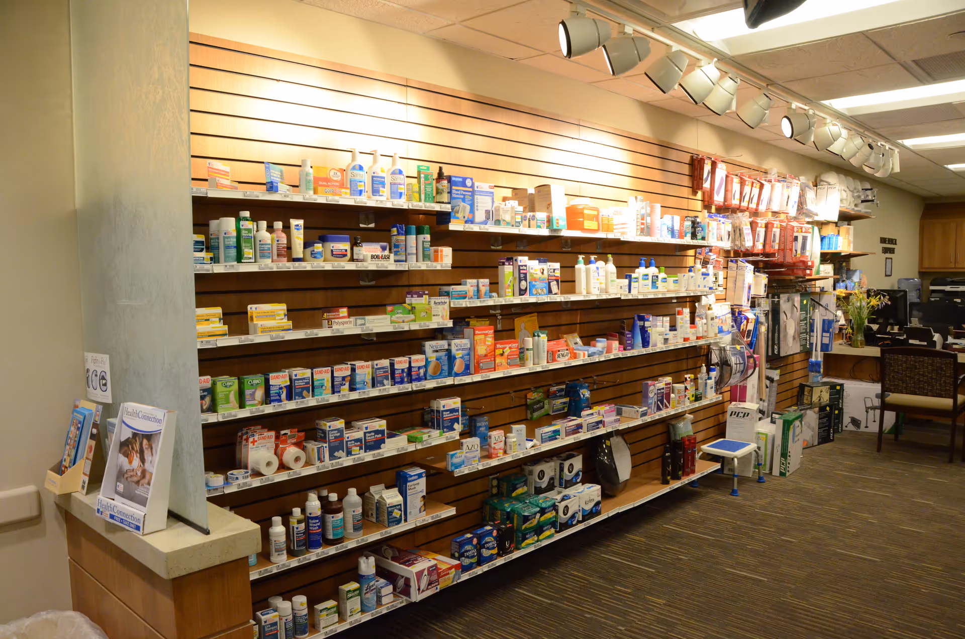 Interior pharmacy area with long shelves stocked with medicines and supplies.
