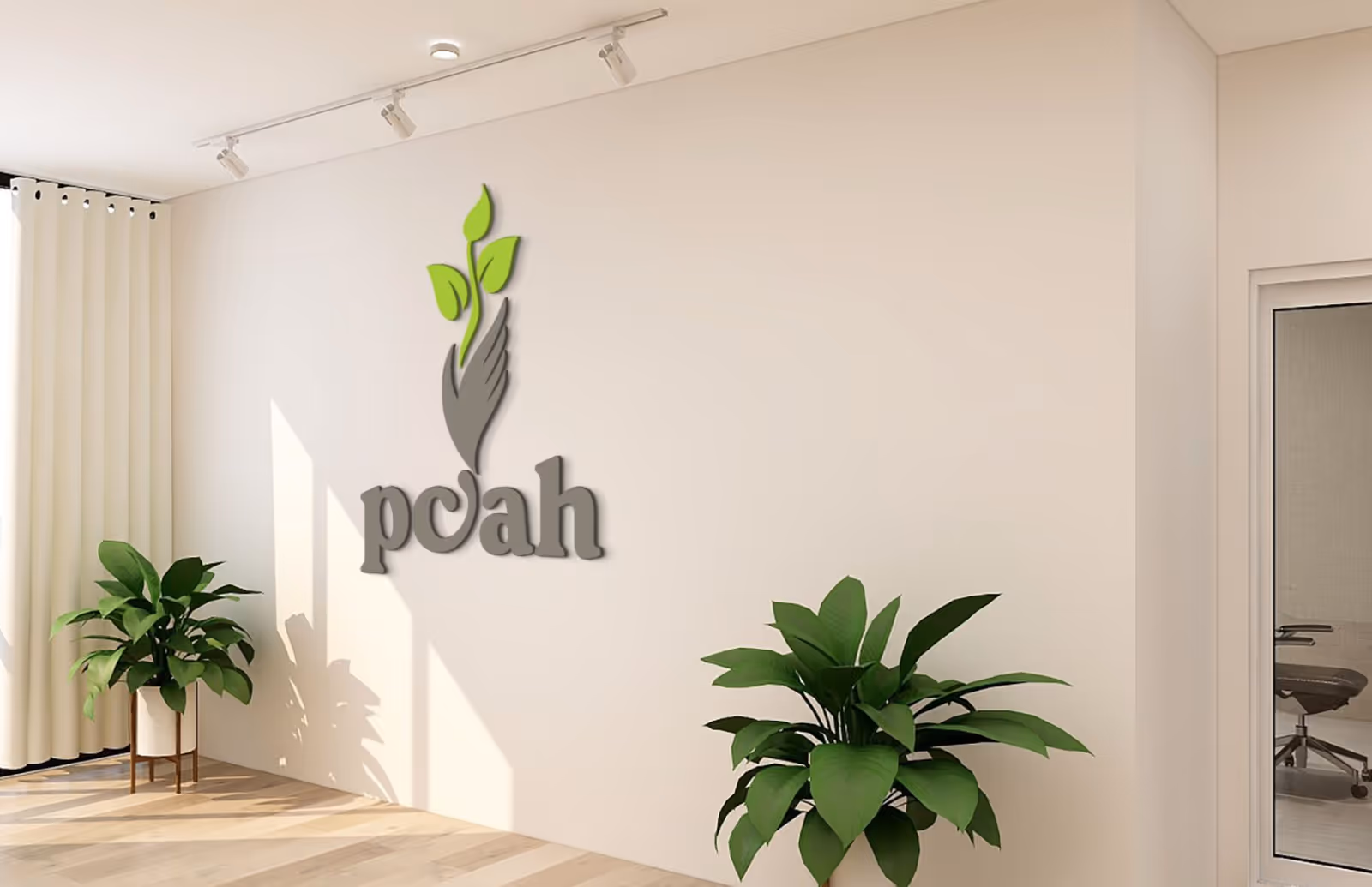 White lobby wall with the 'pcah' logo and green plants.