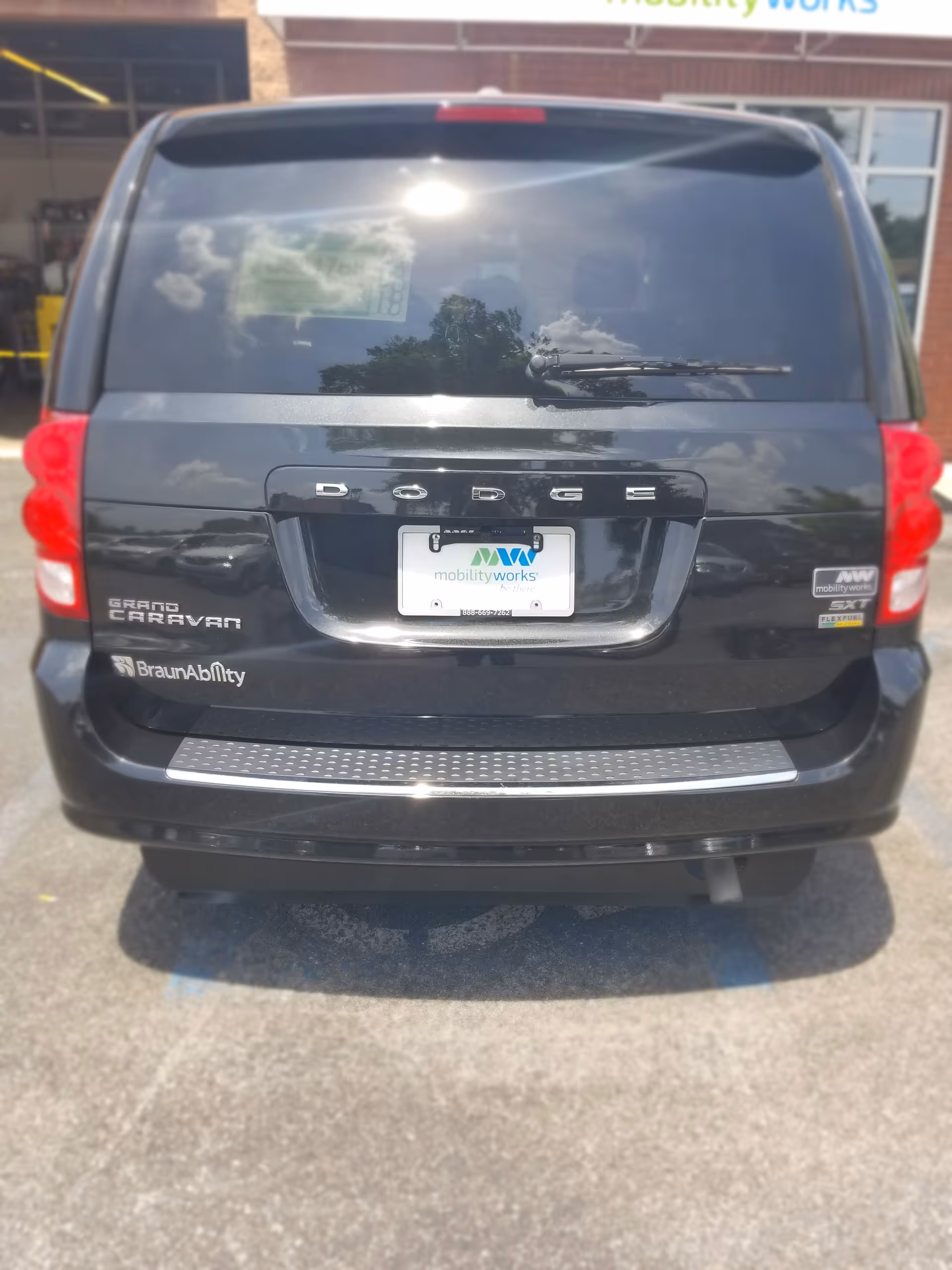 Rear view of a black Dodge Grand Caravan with MobilityWorks plate in a parking lot.