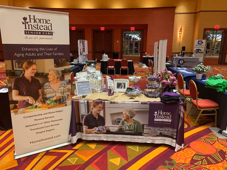 Indoor conference booth for Home Instead Senior Care with banners and tables.