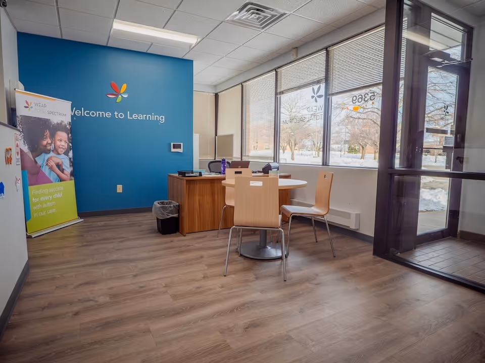 Interior reception area with blue wall sign 'Welcome to Learning', round table and chairs.