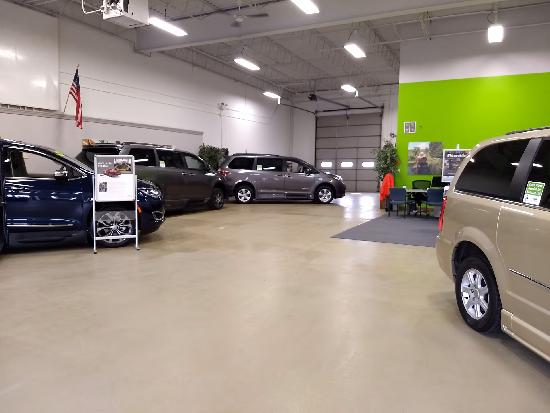 Inside MobilityWorks showroom with several vans parked indoors and a green accent wall.