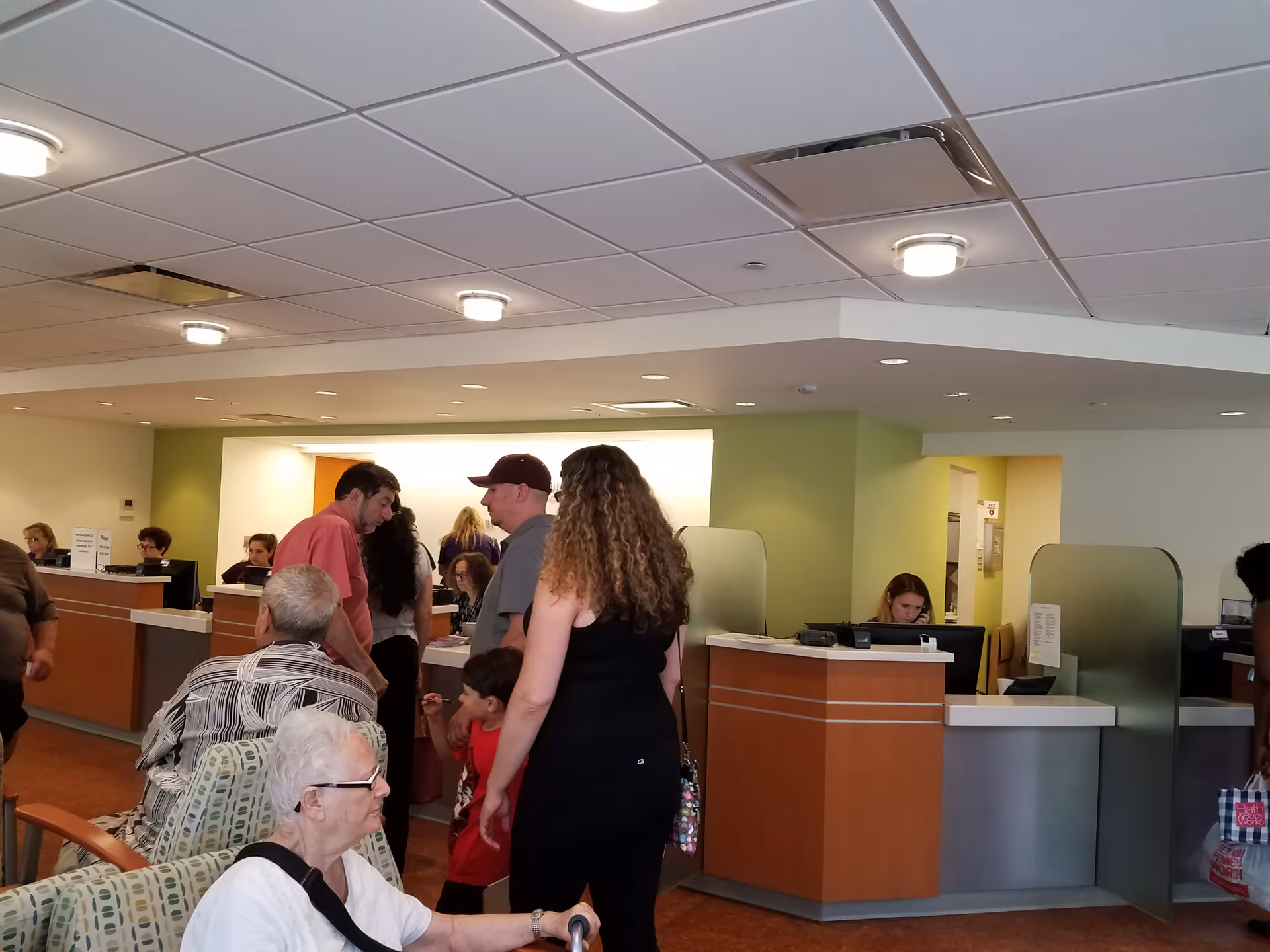 Busy clinic lobby with reception desks and residents awaiting assistance.