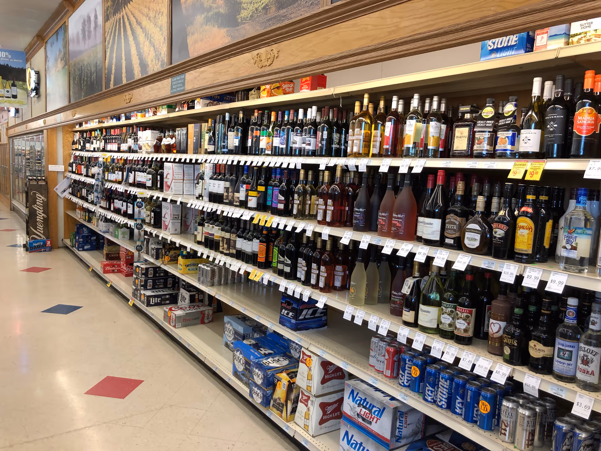 Aisle of liquor bottles lined up on shelves inside Discount Drug Mart.