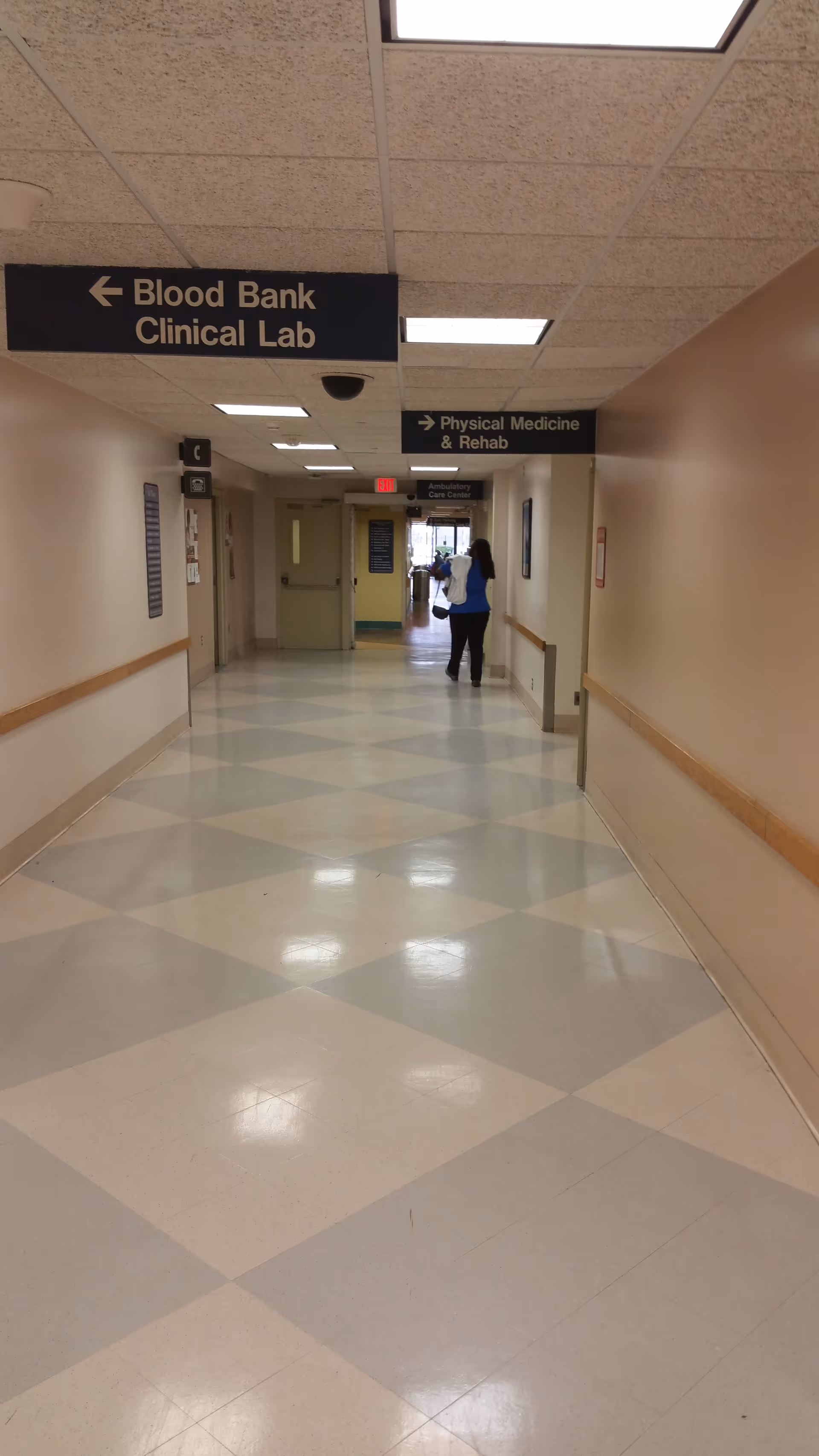 Hospital hallway with overhead signs to Blood Bank, Clinical Lab, and Physical Medicine & Rehab.