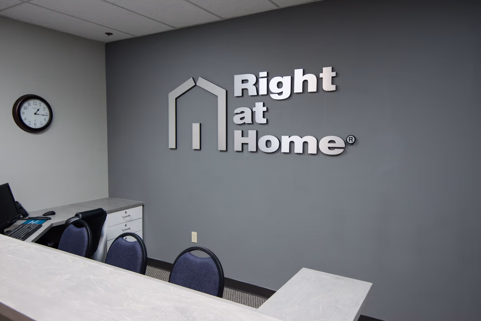 Reception area with a desk, chairs, and a large Right at Home sign on the wall