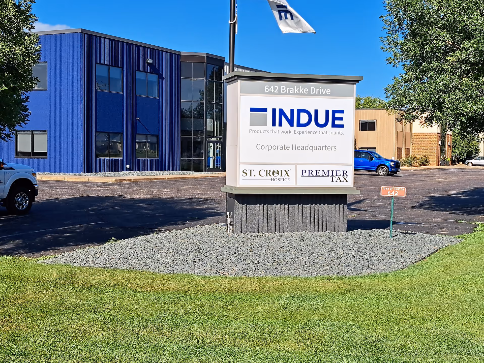 Blue two-story corporate building with glass entrance and a large sign in front.
