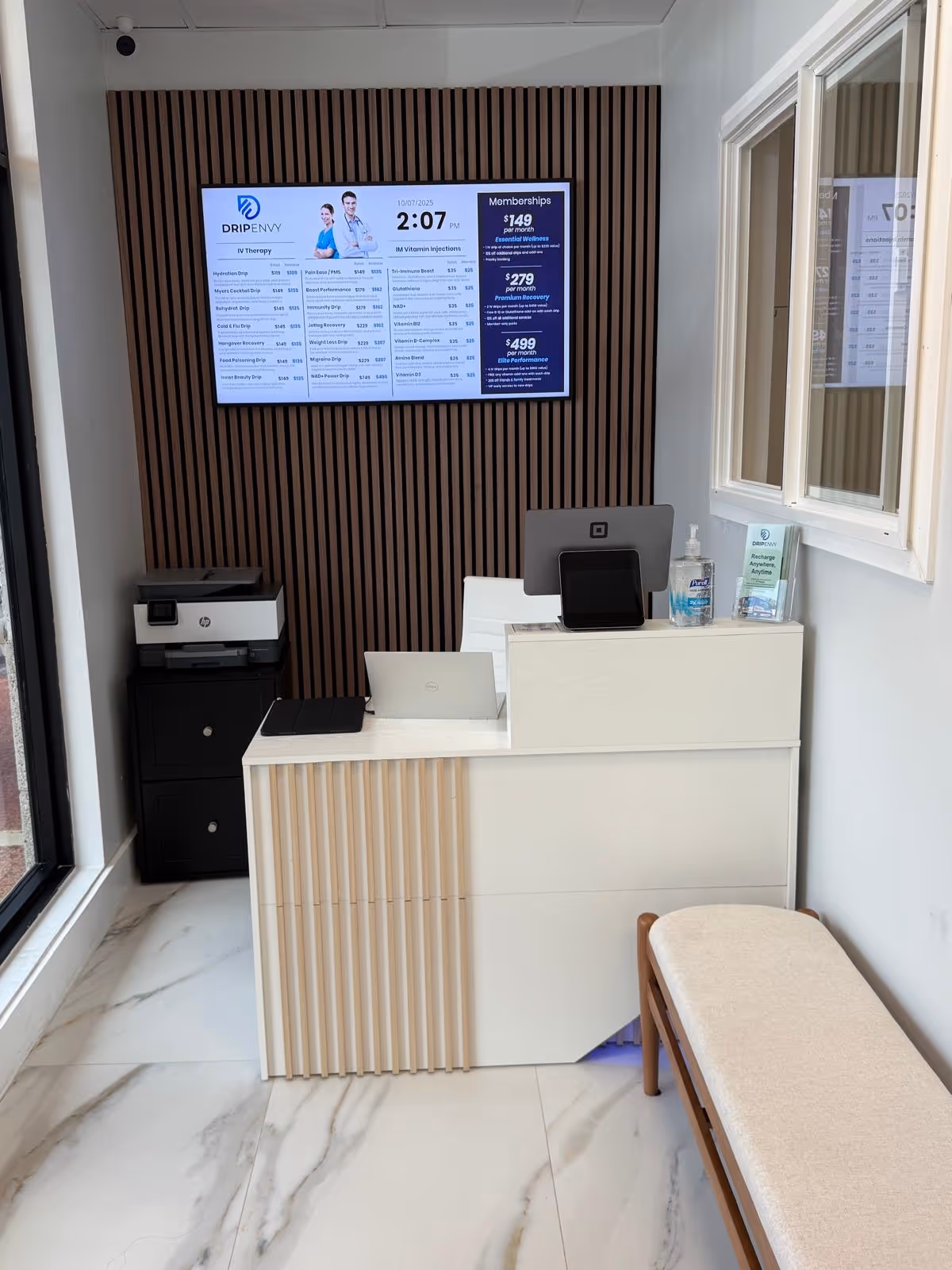 Reception desk with computer and wall-mounted digital display in a modern interior.
