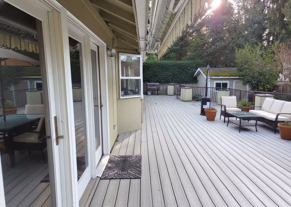 Wooden outdoor deck with seating area and sliding glass doors to interior.