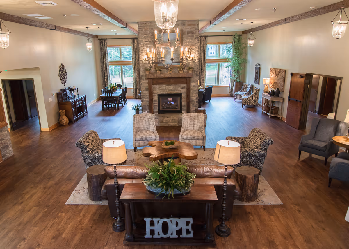 Spacious senior living lounge with a stone fireplace and multiple seating areas.