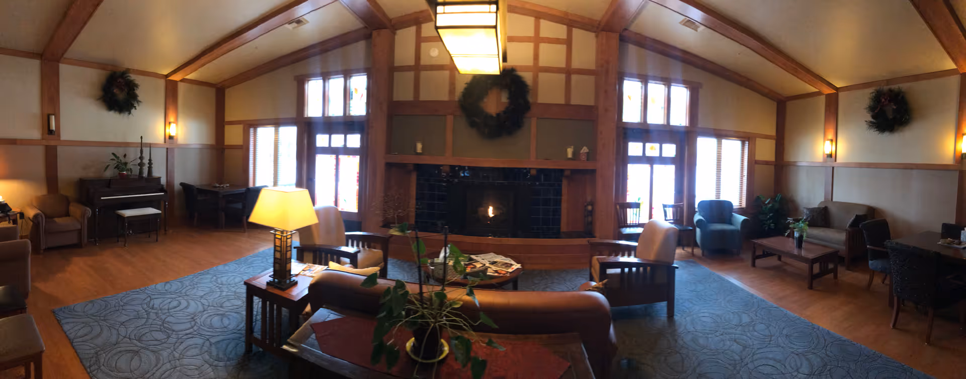Cozy indoor lounge with sofas, chairs, and a central fireplace.