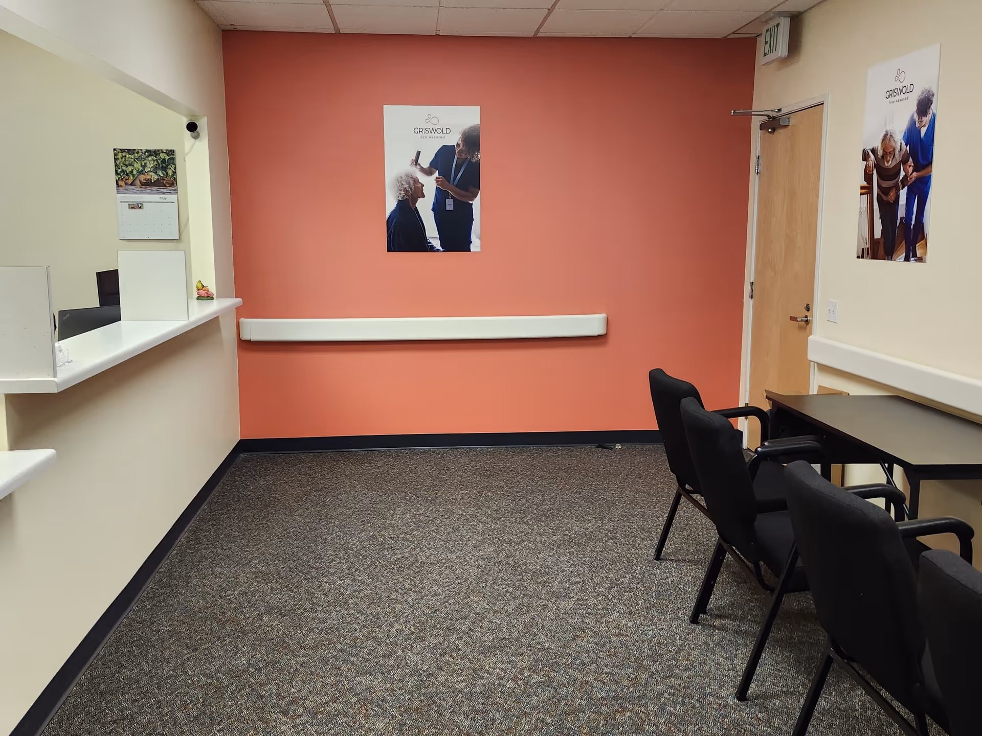 Interior reception area with coral wall, a counter, and several chairs.