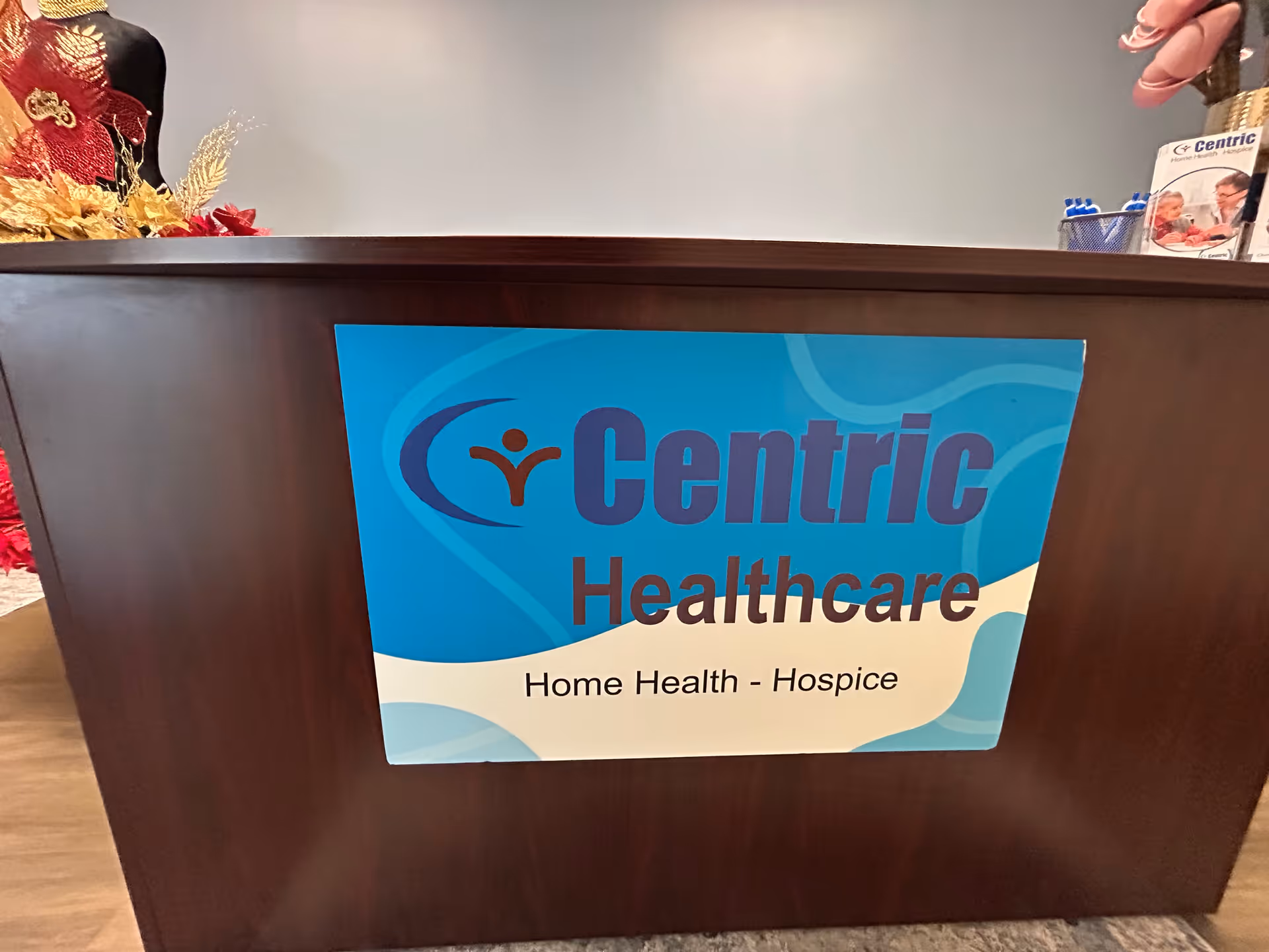 Reception desk with a Centric Healthcare poster and fall decor in a clinical lobby.