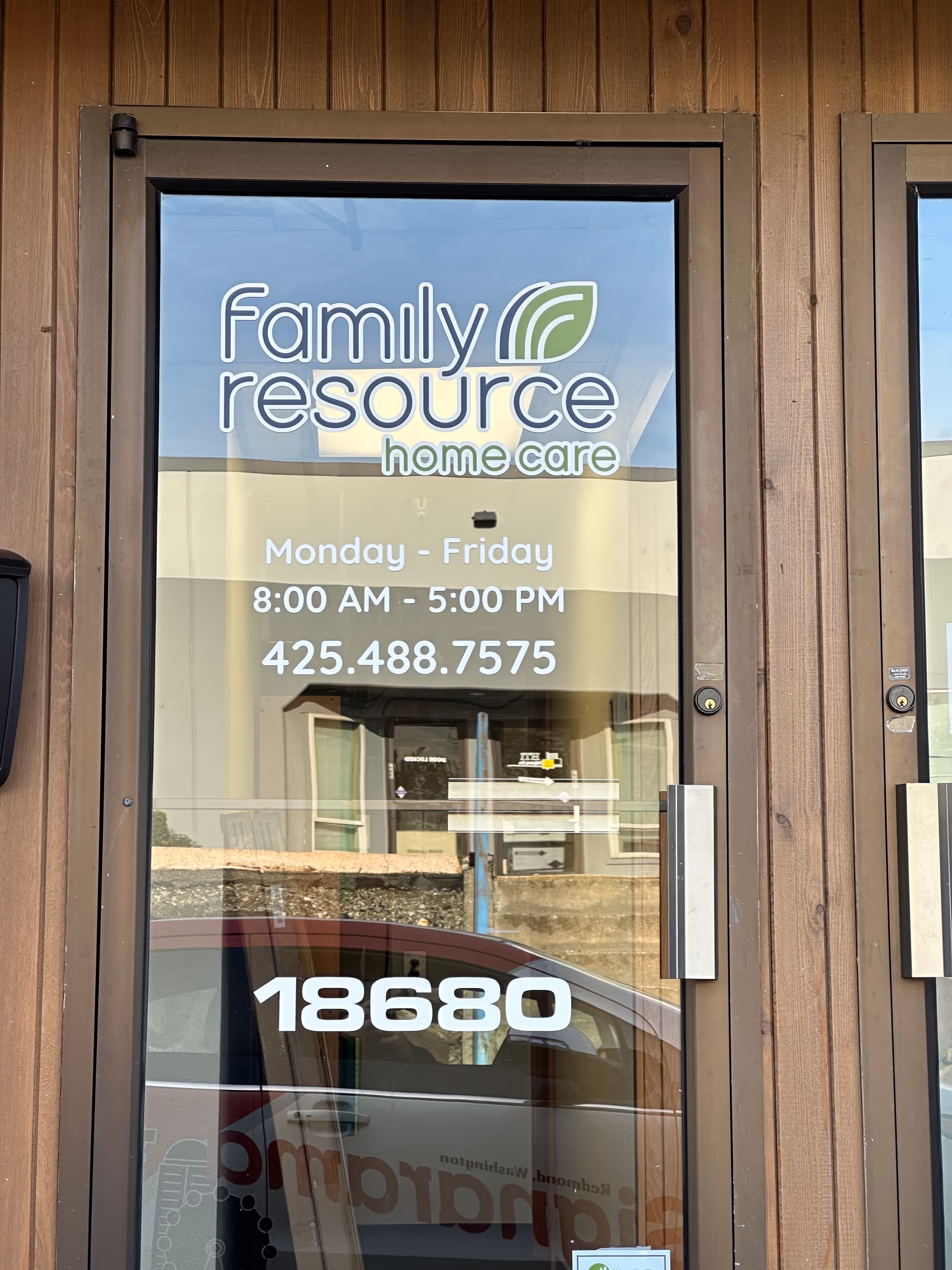 Glass door with Family Resource Home Care logo and hours, wooden exterior.
