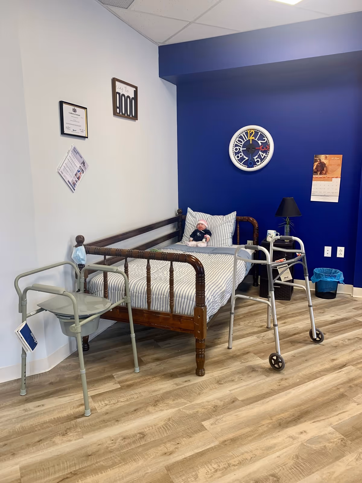 A cozy bedroom in a senior living facility with a bed, walker, and blue accent wall.