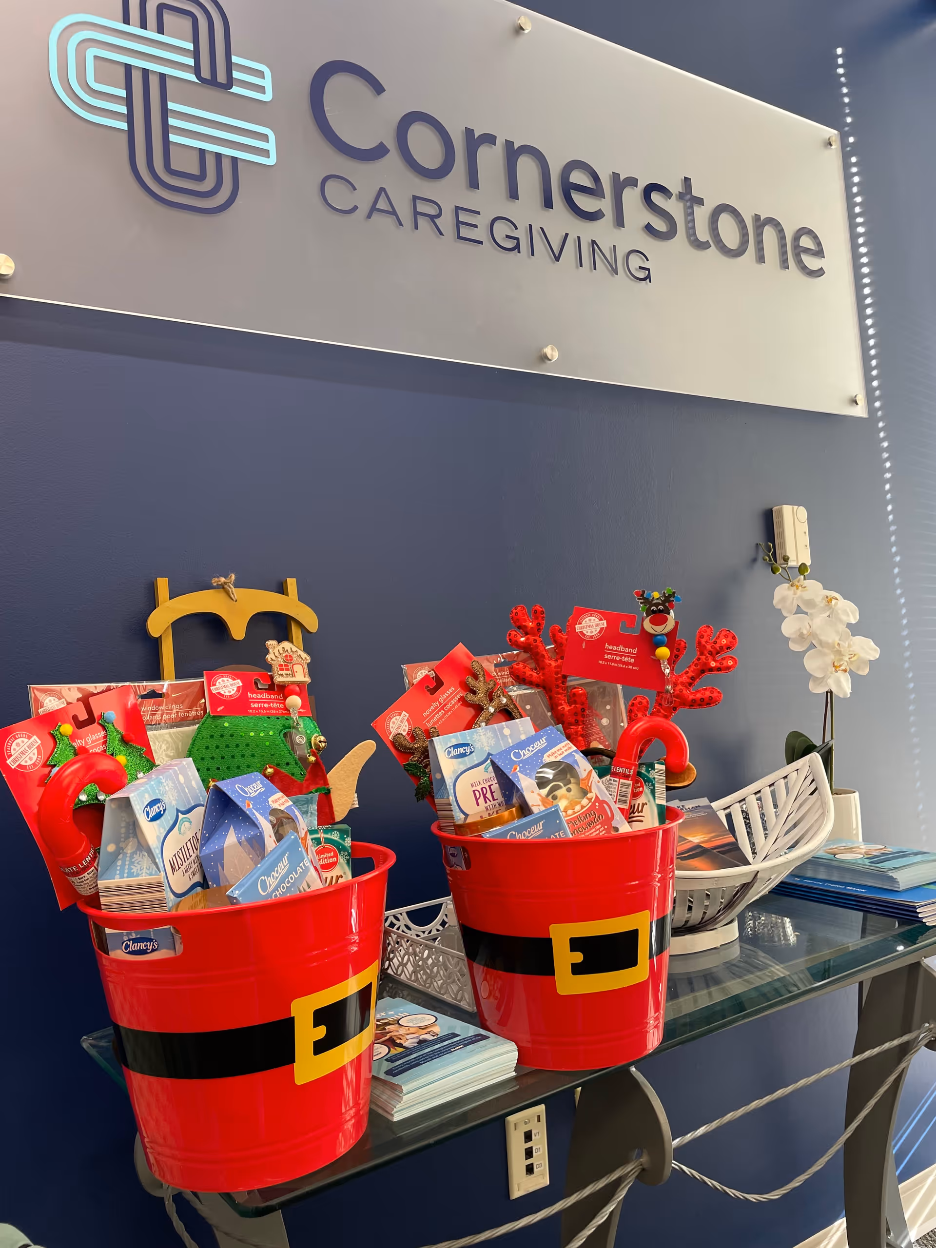 Interior reception area with Cornerstone Caregiving sign and red holiday gift buckets.