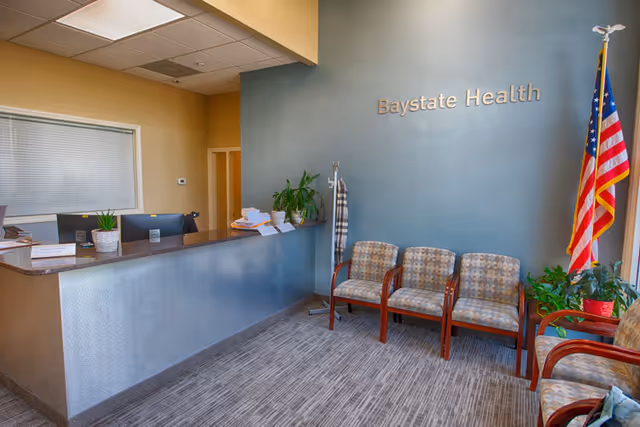 Reception area of Baystate Home Health in West Springfield with blue wall, chairs, and American flag.