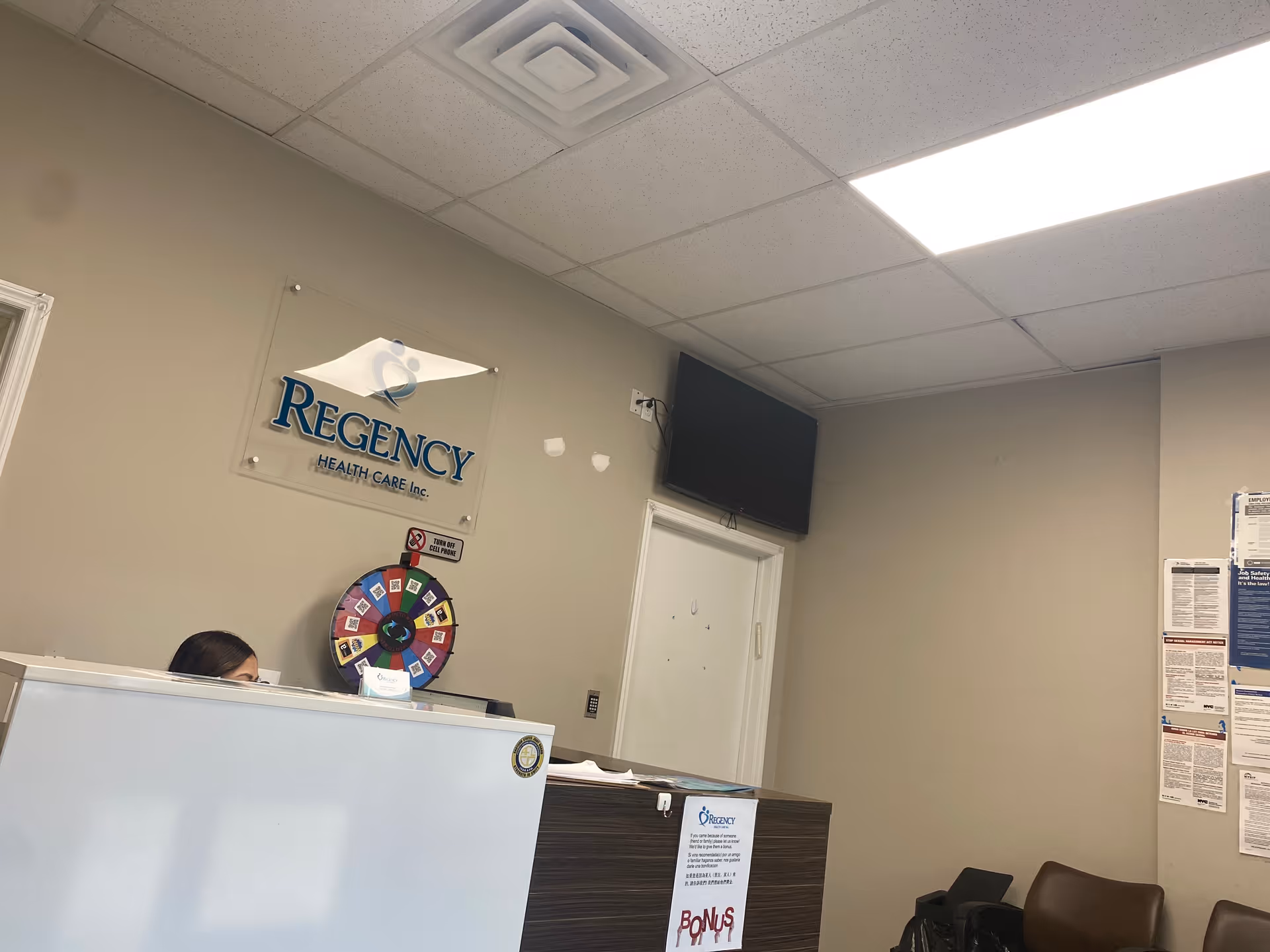 Reception area inside Regency Health Care with sign, spinning wheel, and seating