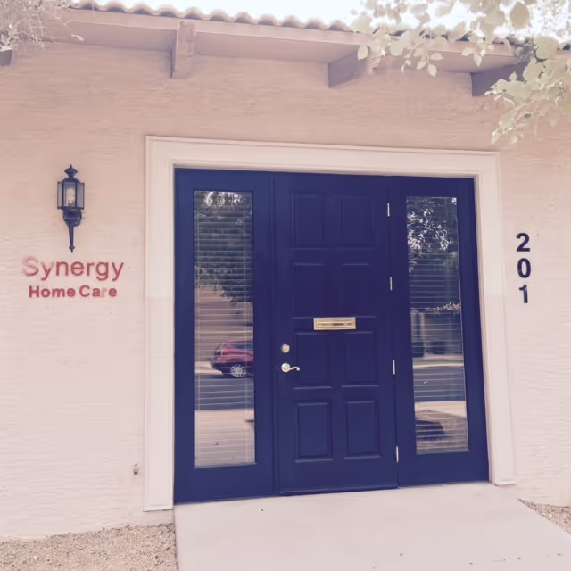 The image shows a blue front door entry with Synergy HomeCare sign on beige exterior wall.
