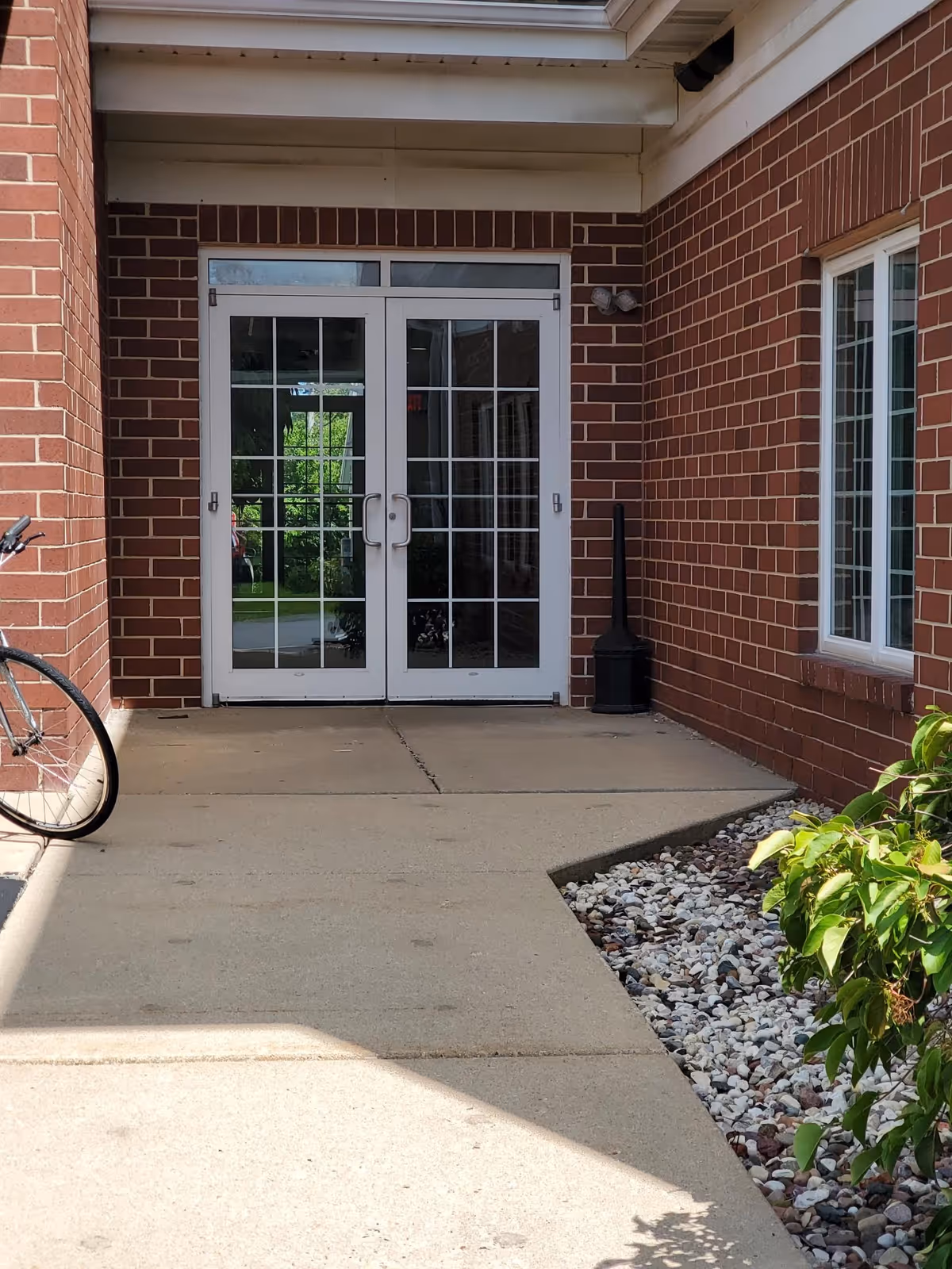 White double doors with glass panes form a brick building entrance.