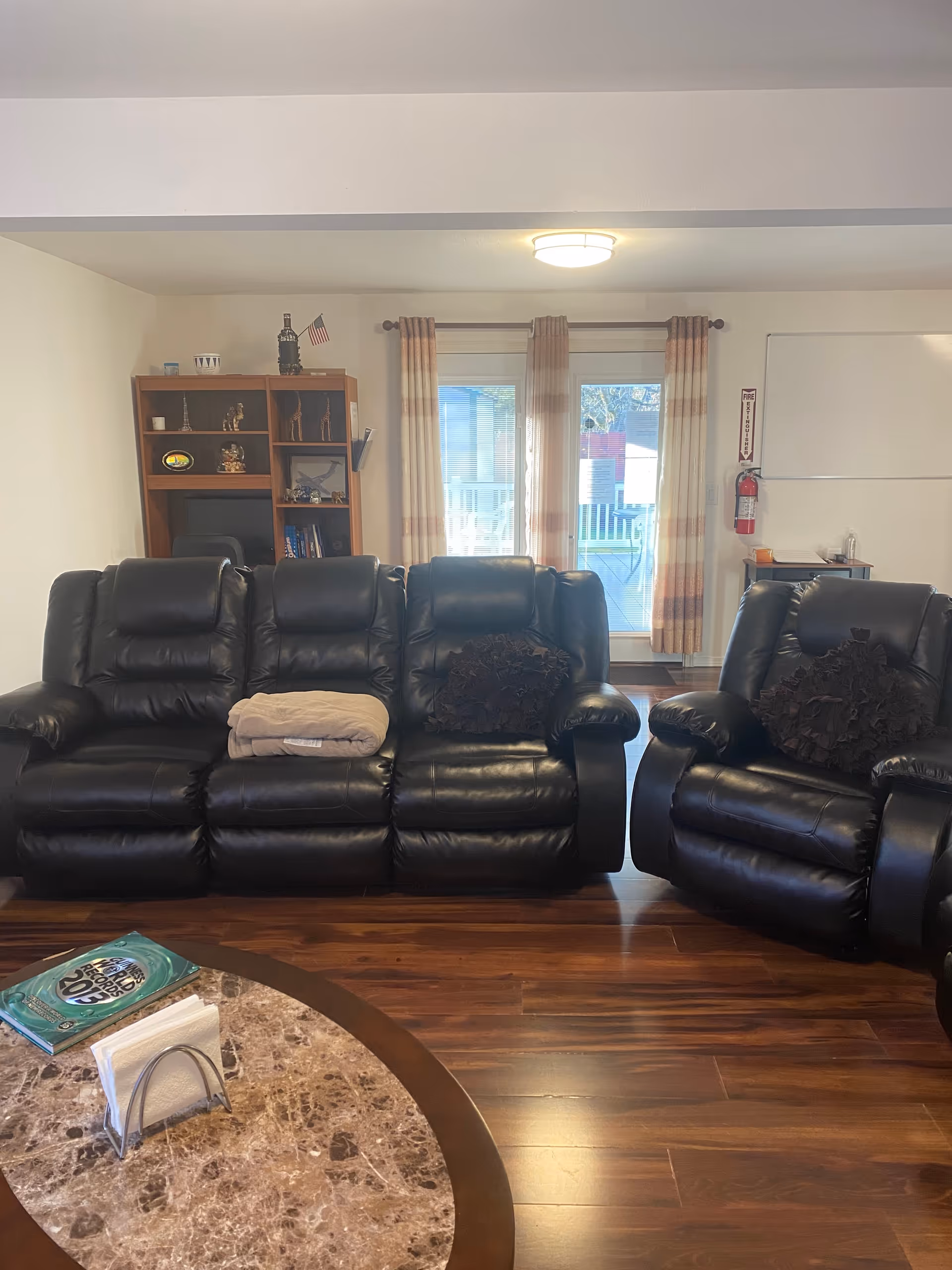 Cozy living room with black leather sofas, a round marble coffee table, and a bookshelf.