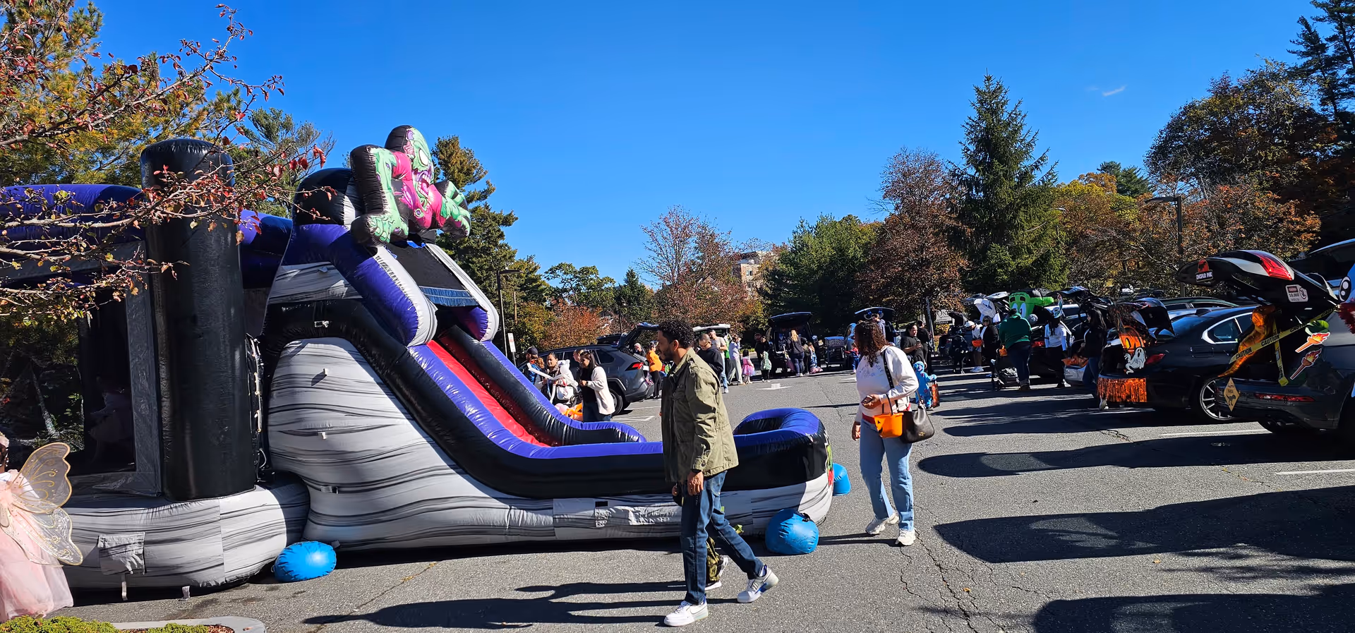 Outdoor parking lot with a large inflatable slide and people at a community event.
